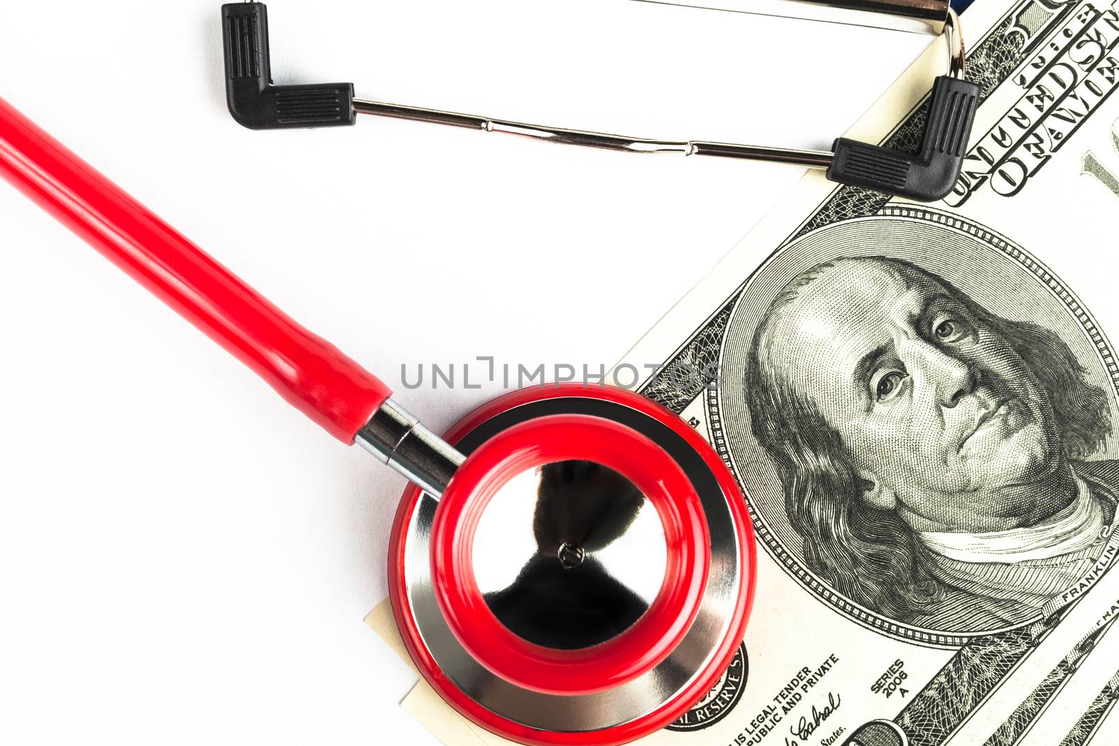 Red stethoscope on a empty   clipboard  with a pile of dollars