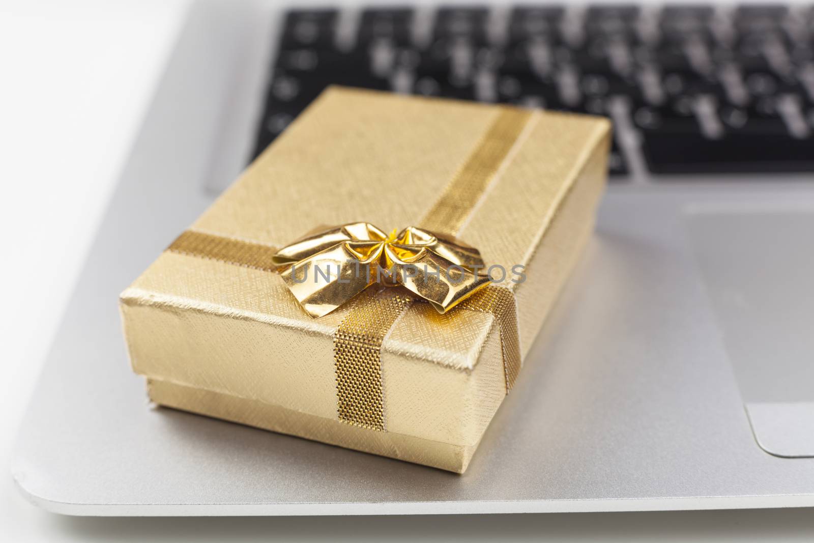 gold gift box on silver laptop closeup 