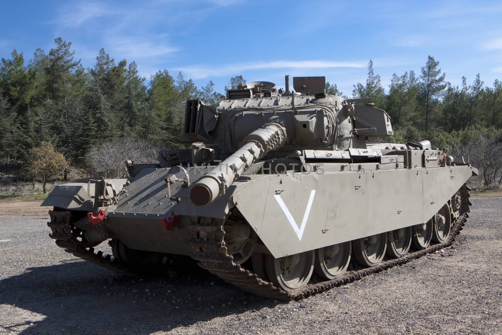 old israelian war tank with green trees and blue sky in the background 