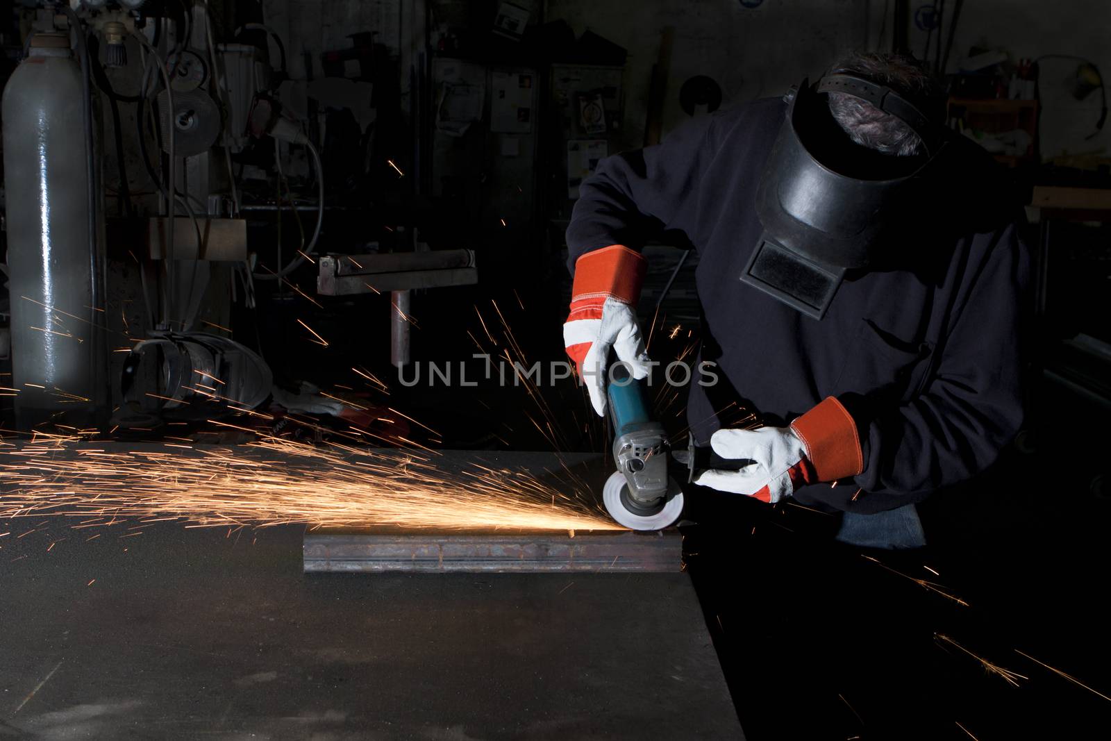 man working in a heawy industry workshop with a grinder spartks alying all over