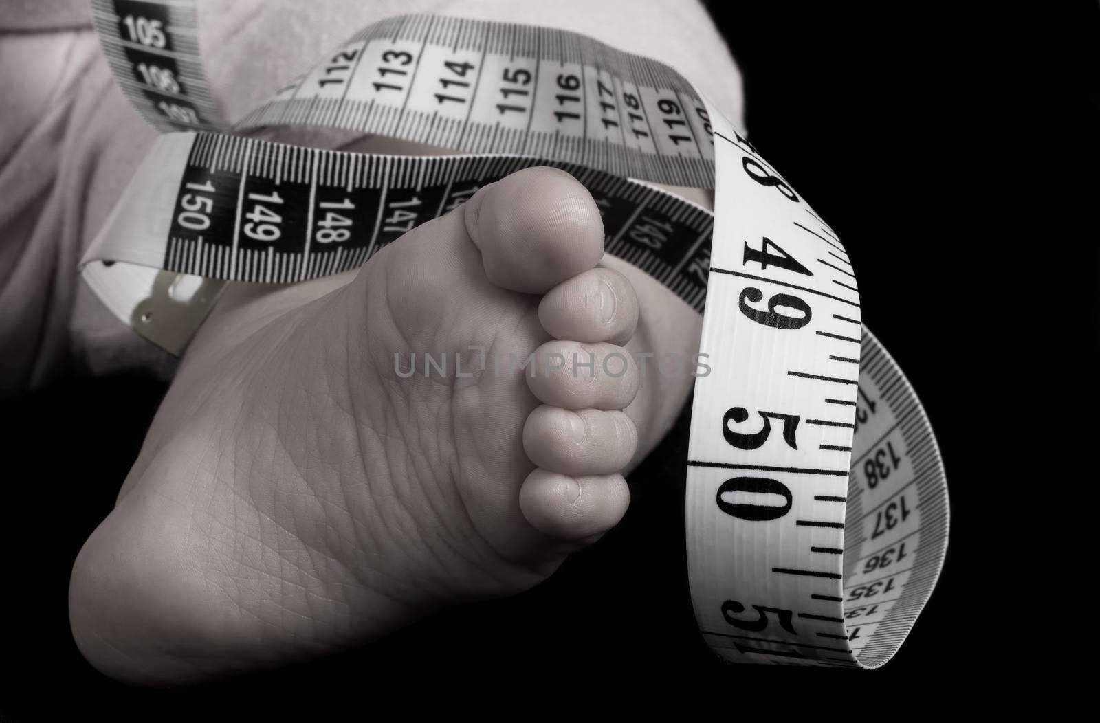 little baby foot with a meter on black background low saturation