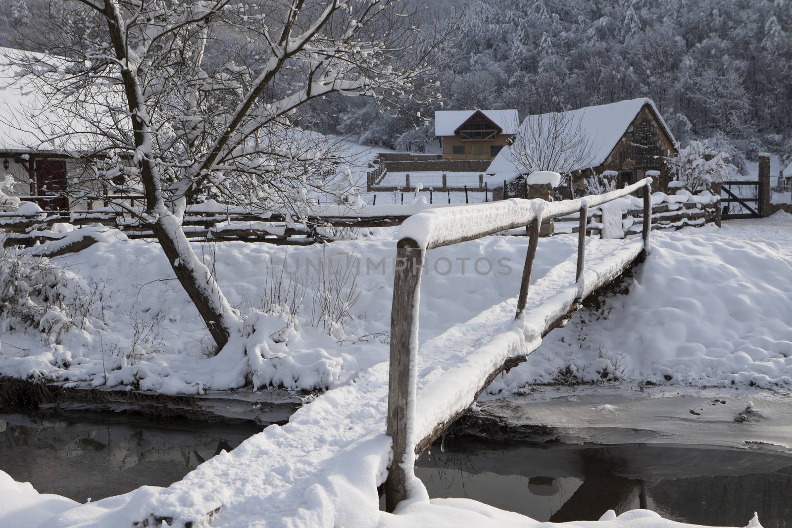 a small bridge covered with white snow in a mountain village in eastern europe