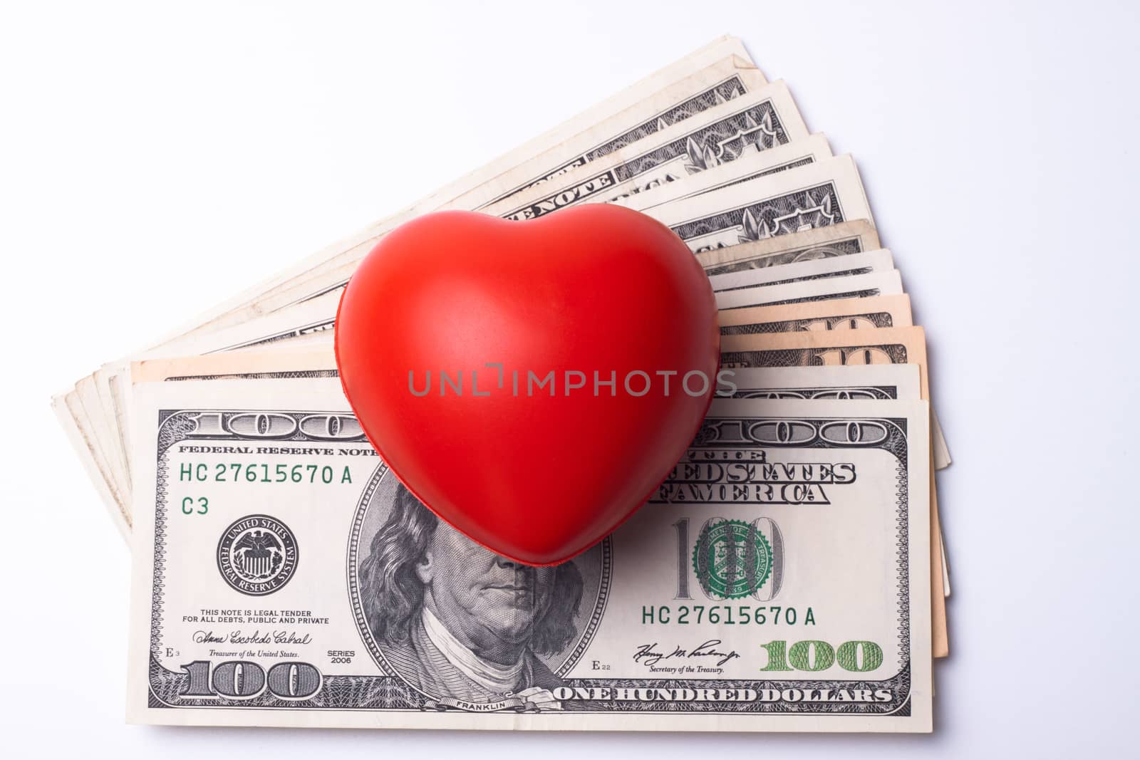 red heart on top of dollar bank notes isolated on white