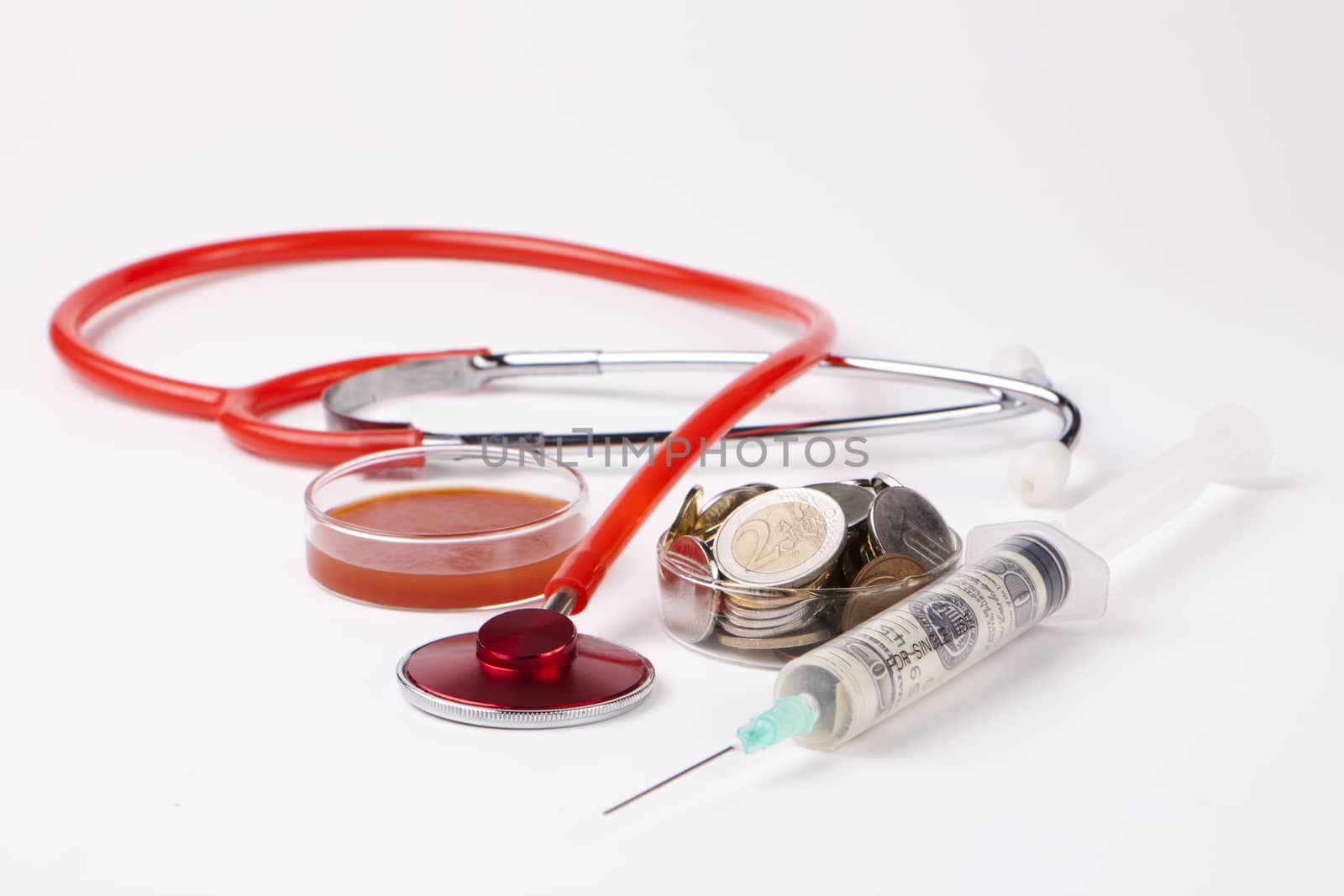 helthcare cost money coins and bills with a red stethoscope and blood sample