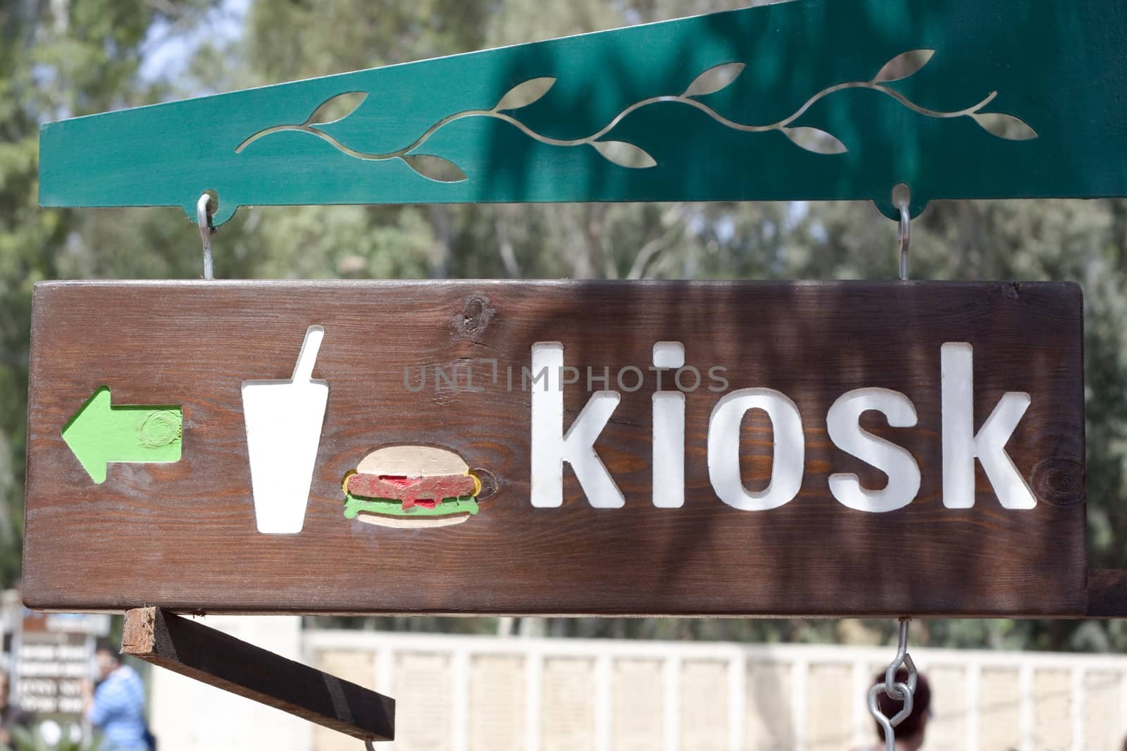 a wood sign with a green arrow with a hamburger and kiosk