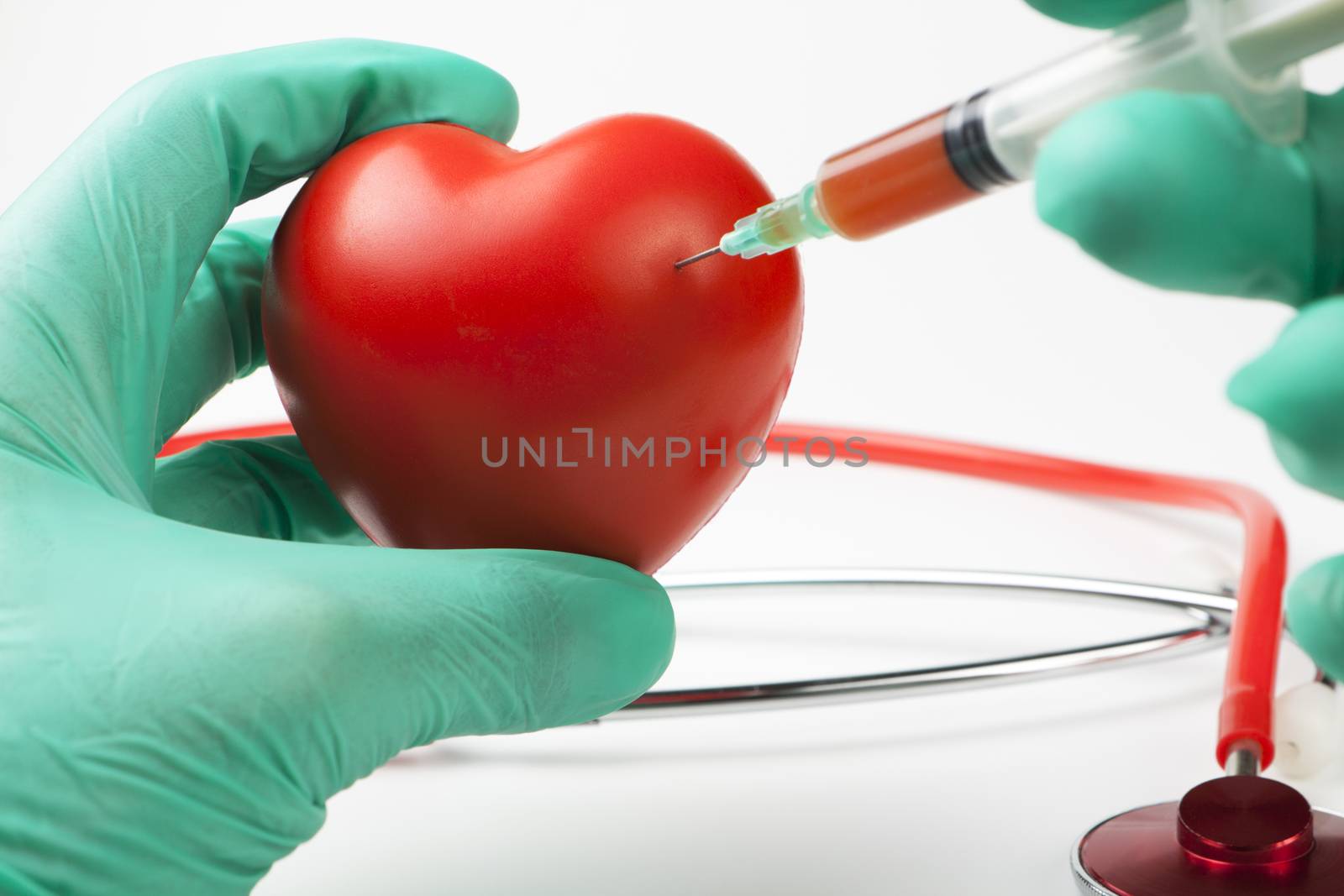 injecting blood int o a big red heart by two hands with green gloves on white background