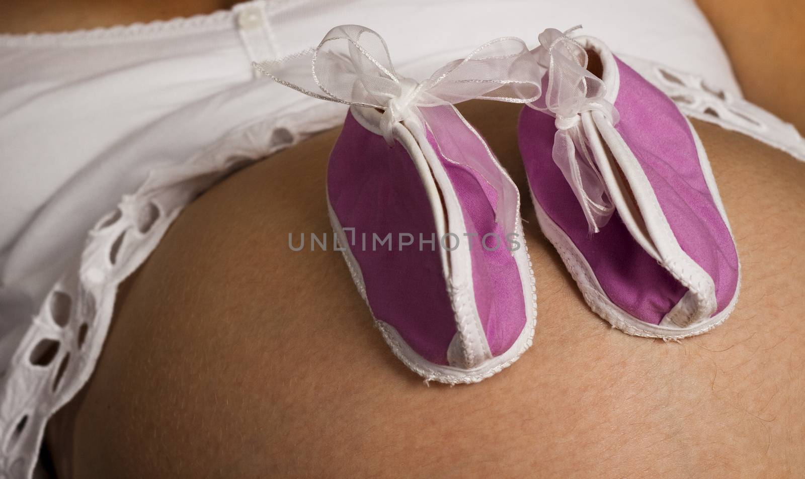 pink baby shoes on a black and white pregnant belly