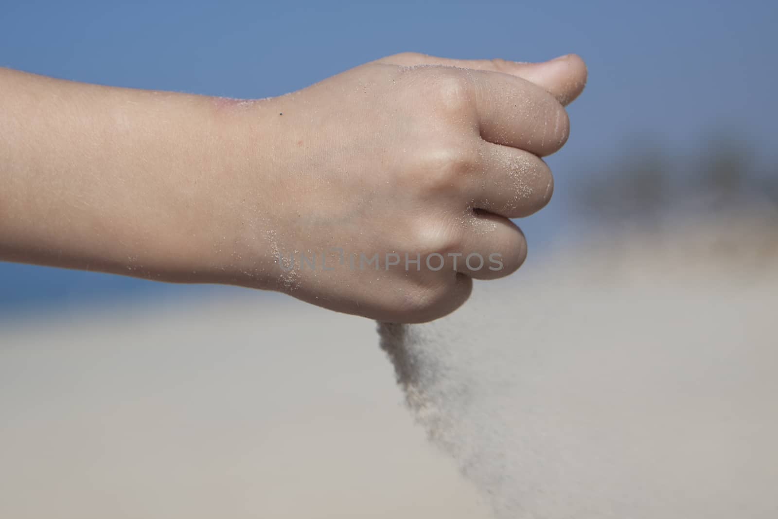 small girl hand pooring san from her fist