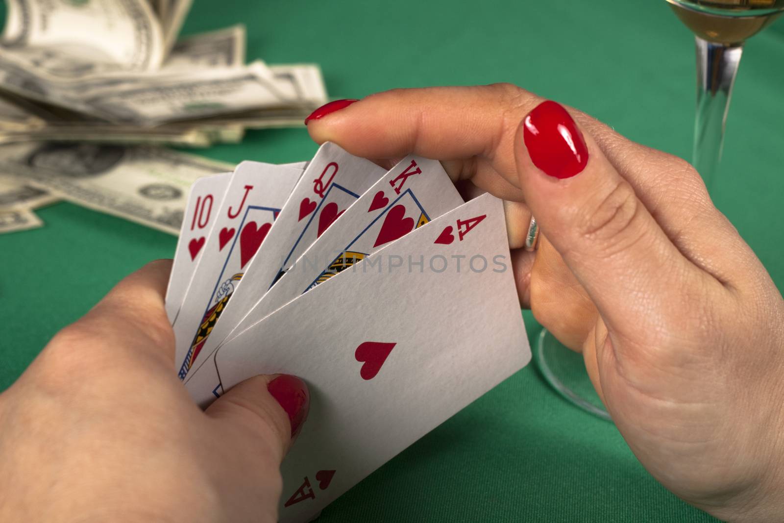 poker cards on green table with dollars and a drink