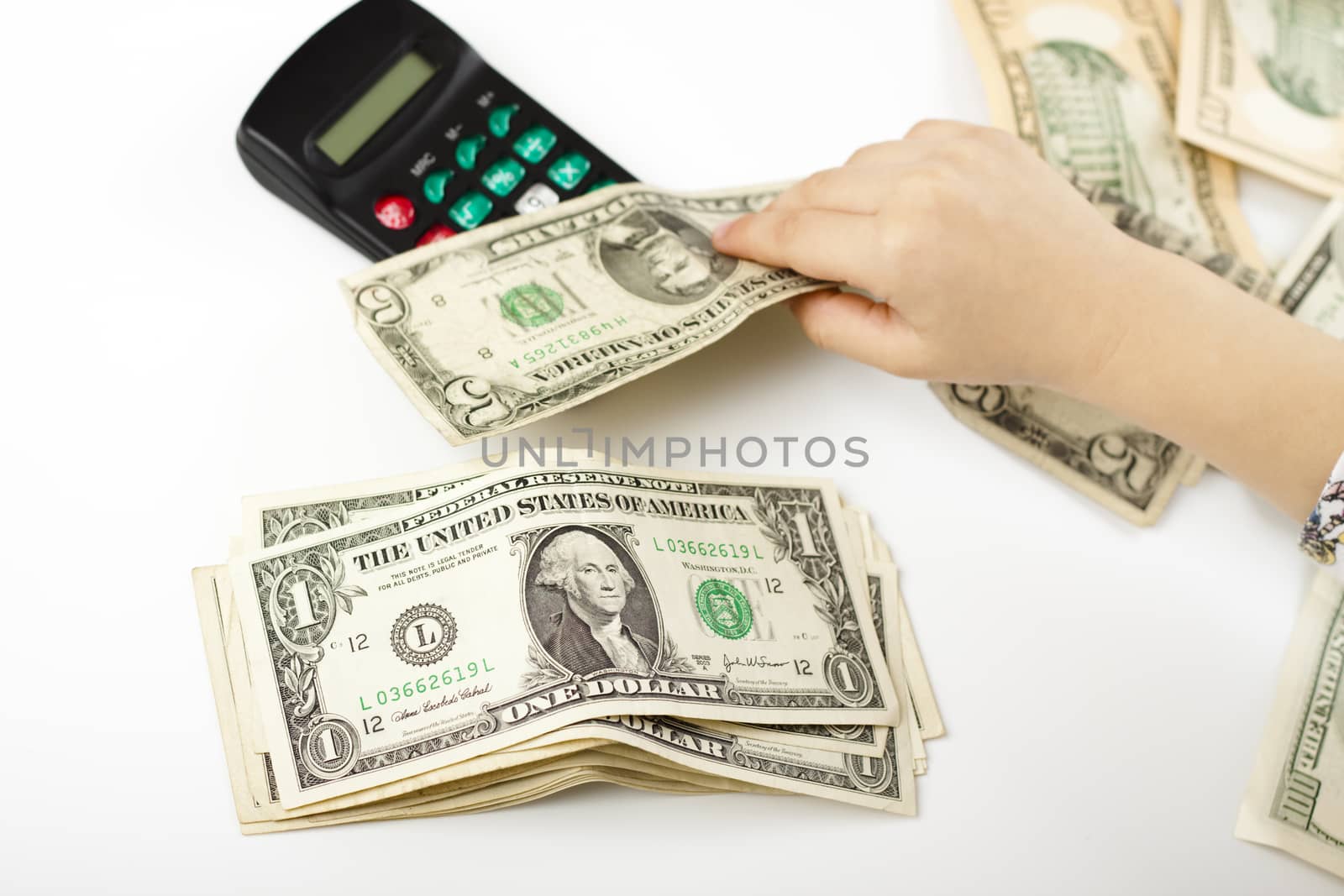 hand separating dollars by type on white background and a black calculator
