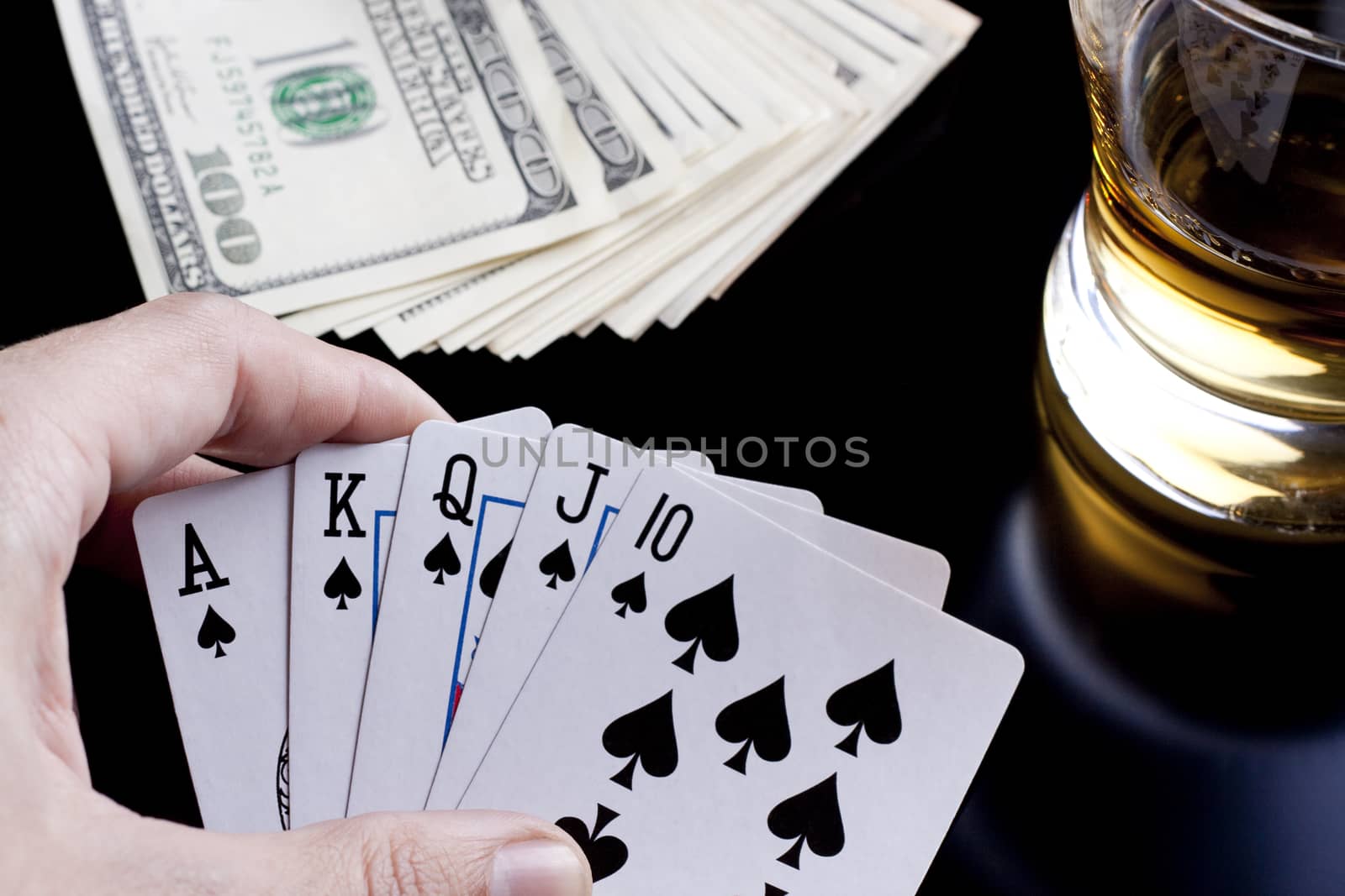 poker playing cards whiskey and some money on a table with reflection