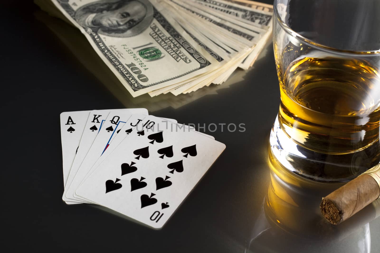 poker playing cards whiskey and some money on a table with reflection