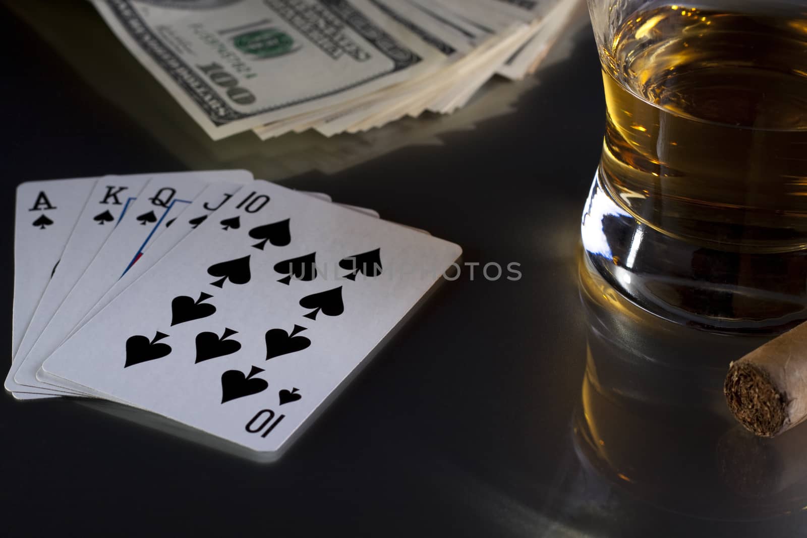 playing card whiskey and some money on a table with reflection