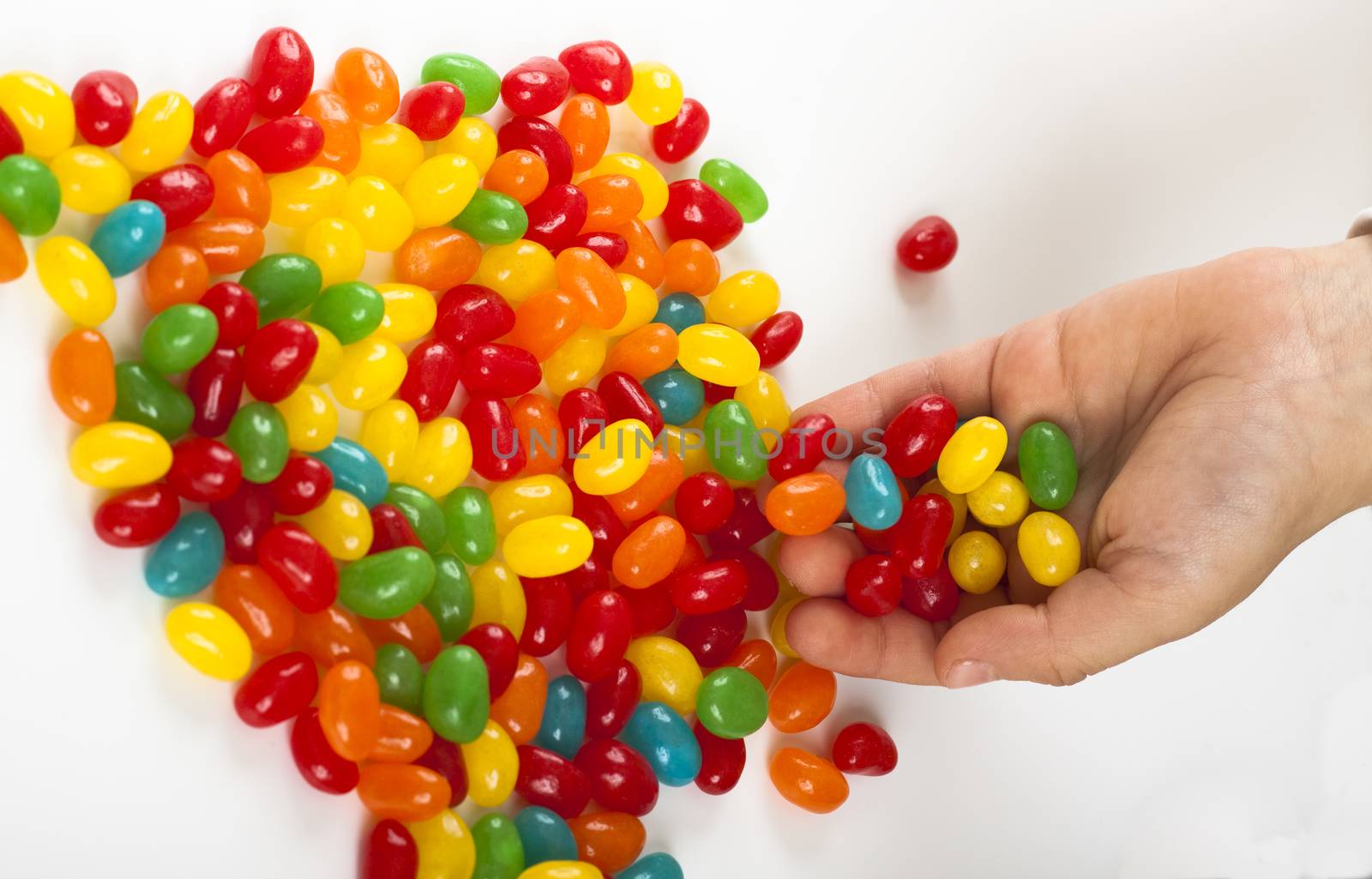 child  holding lot's of colored candy on white background