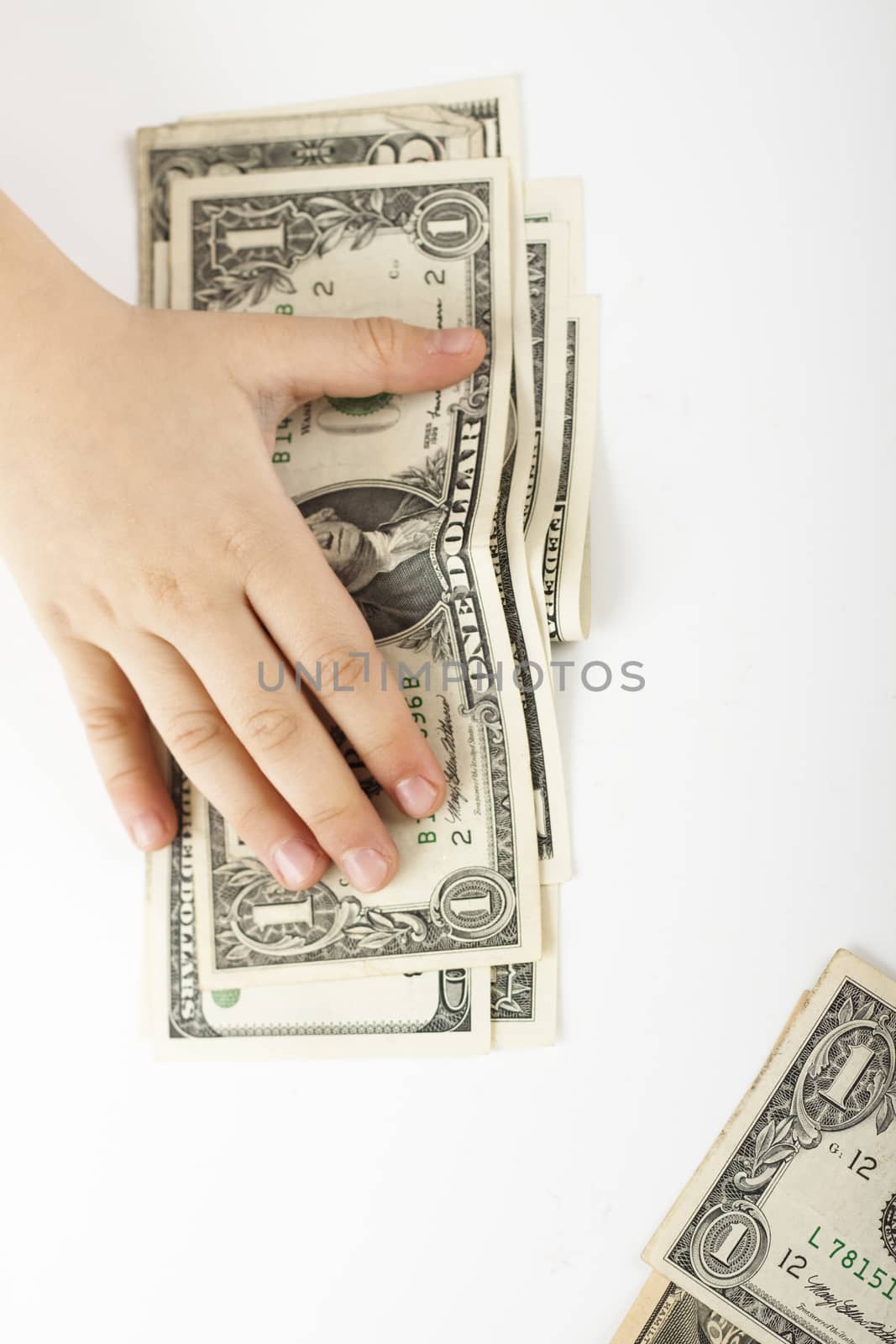 child hand holding down dollar bills on white background