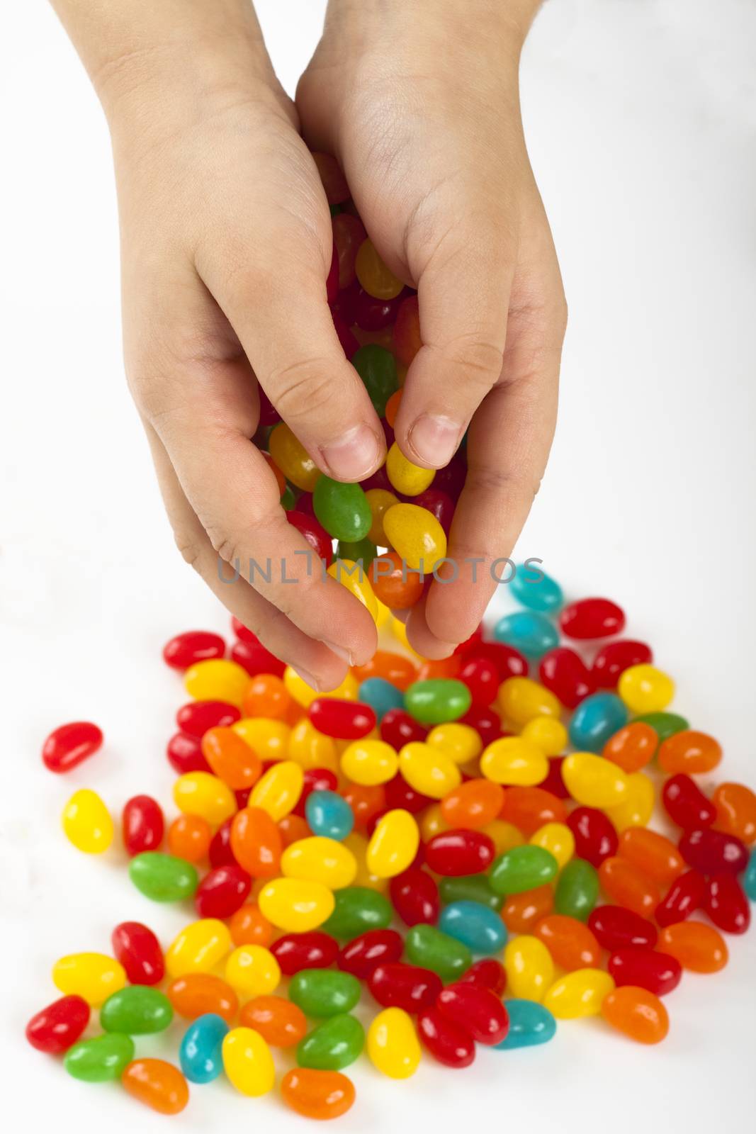child holding colored candy with two hands on white background