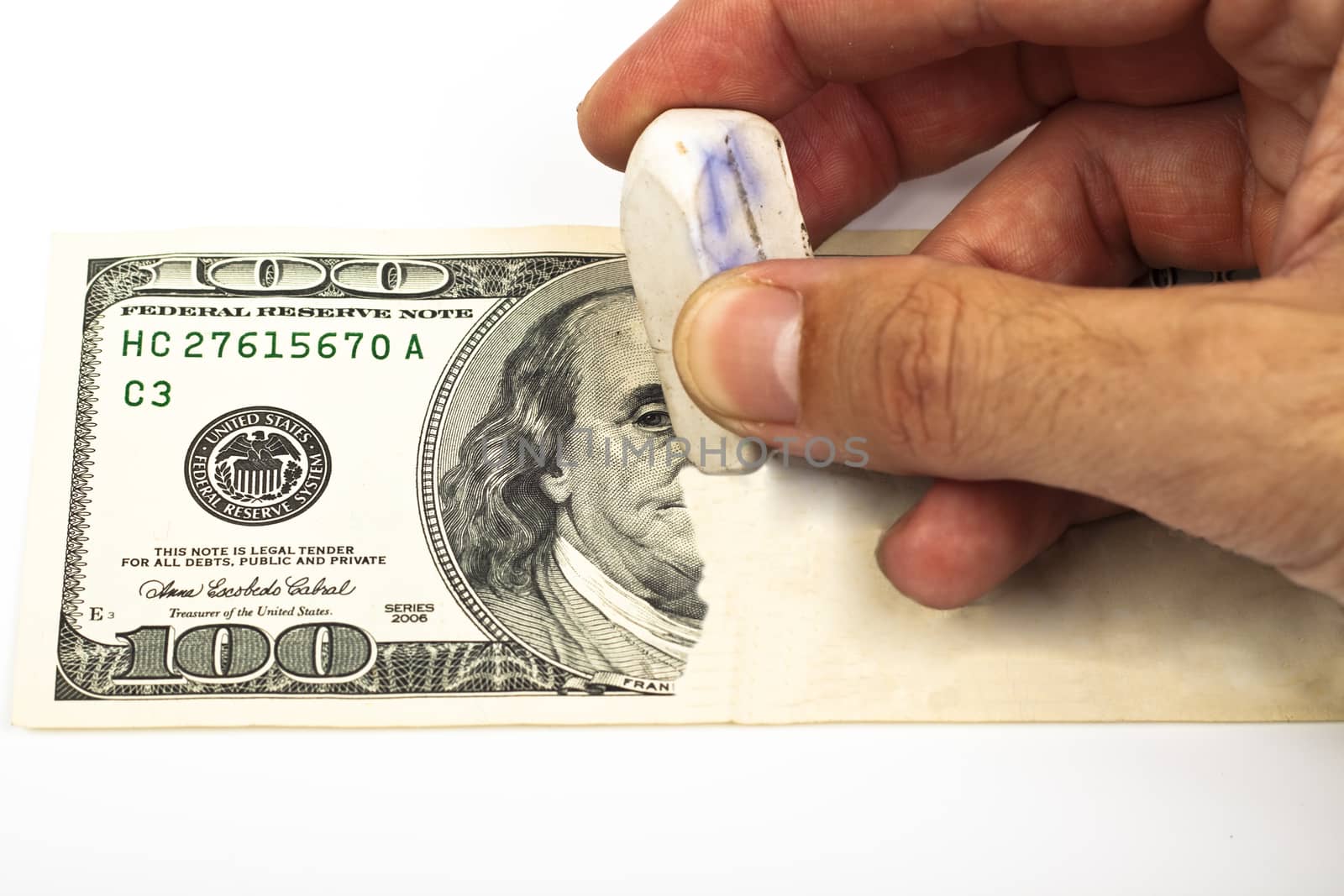 erasing a 100 dollar bill with a white eraser