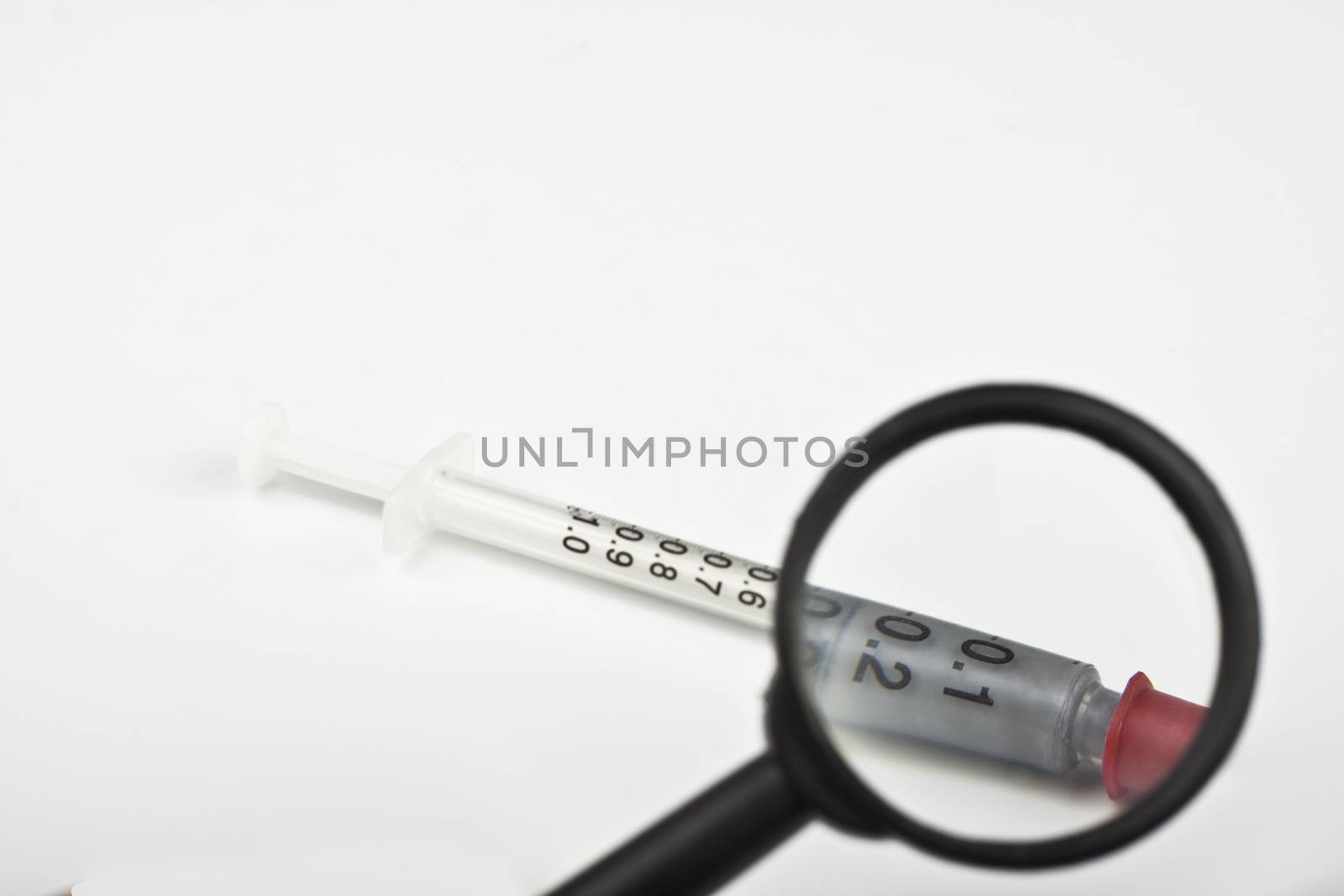 syringe with a magnifying glass on white background
