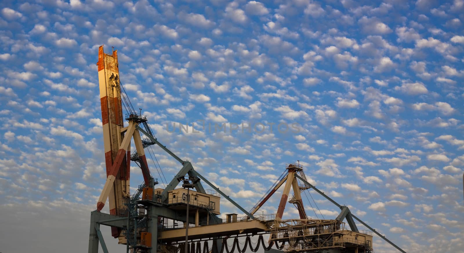 port crane with blue cloudy sky at sunset