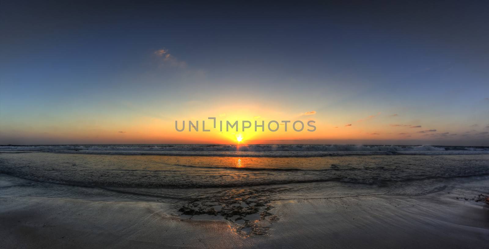 sunset on a beach with cluds sand and blue sky