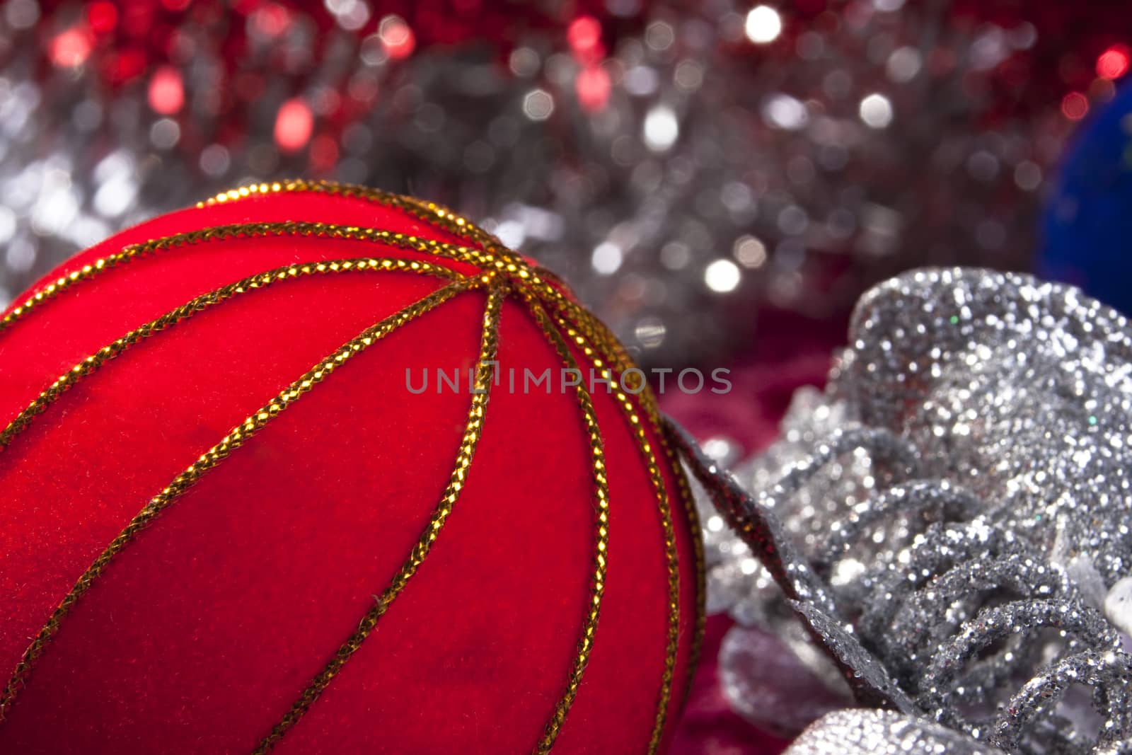 red christams decoration next to a silver with colored light blours in the background