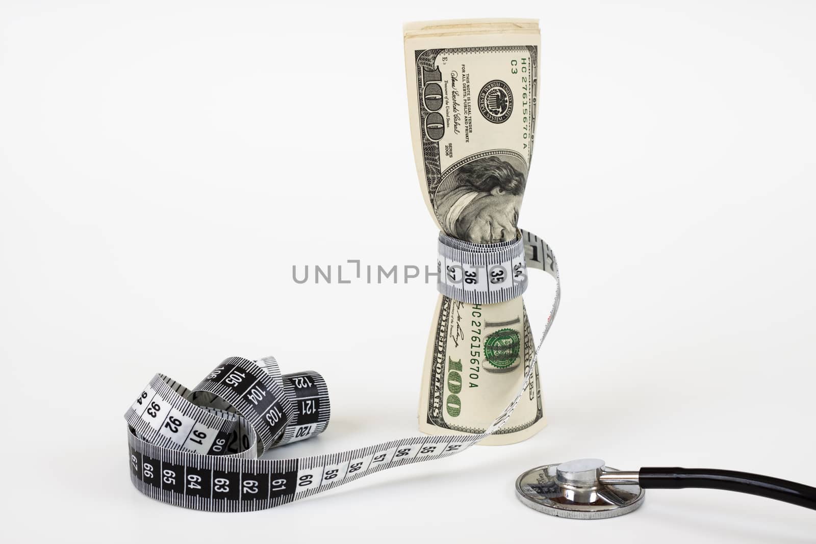 a bunch of dollar bills tighten by a measuring tape  and a stethoscope on white background