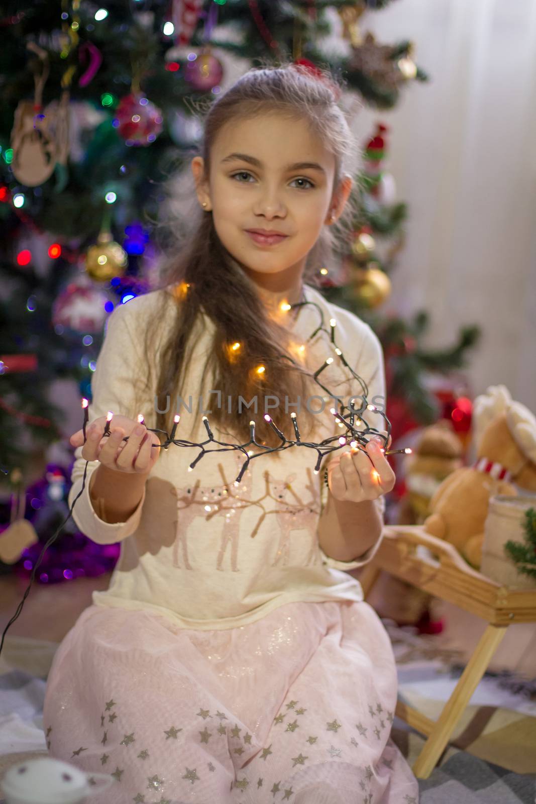 Girl holding lights over Christmas decoration by Angel_a