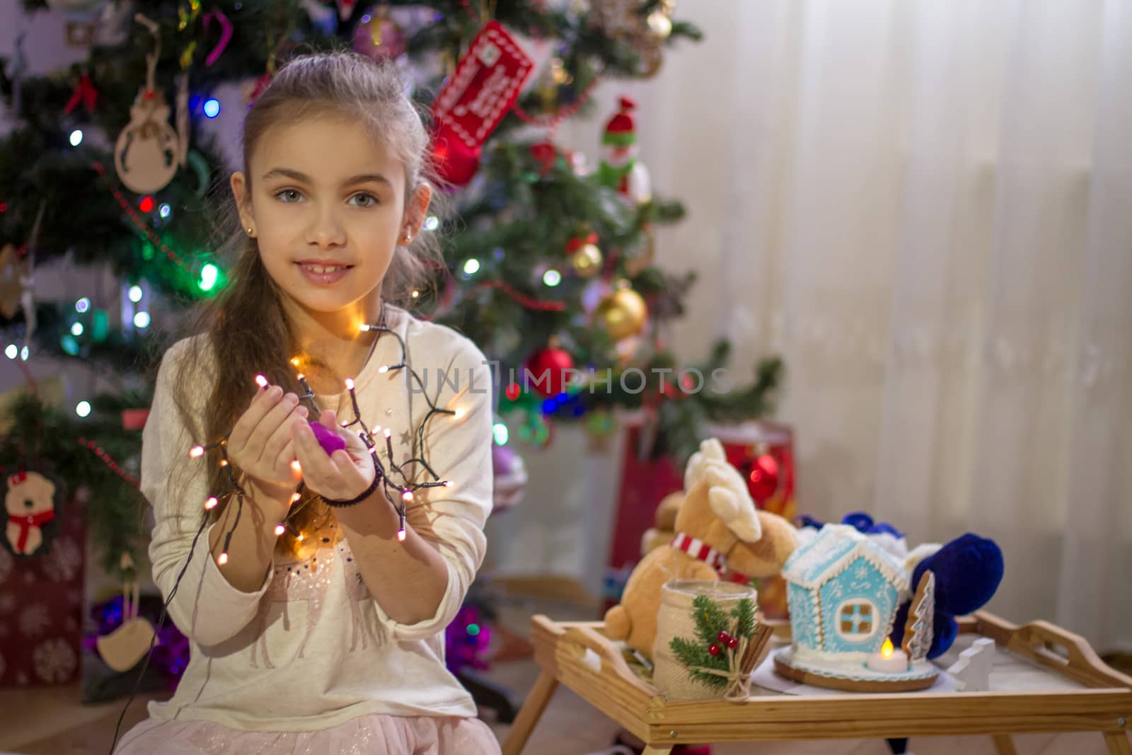 Sweet girl holding lights over Christmas decoration 
