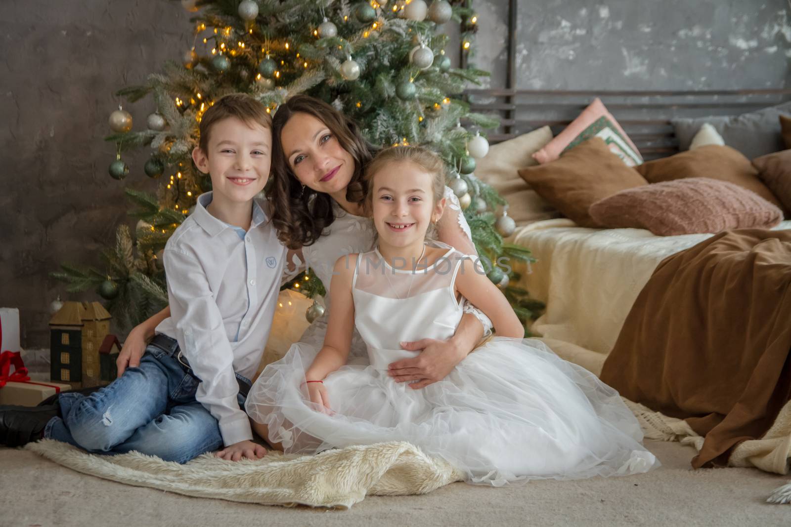 Happy mother and two childre under Christmas tree