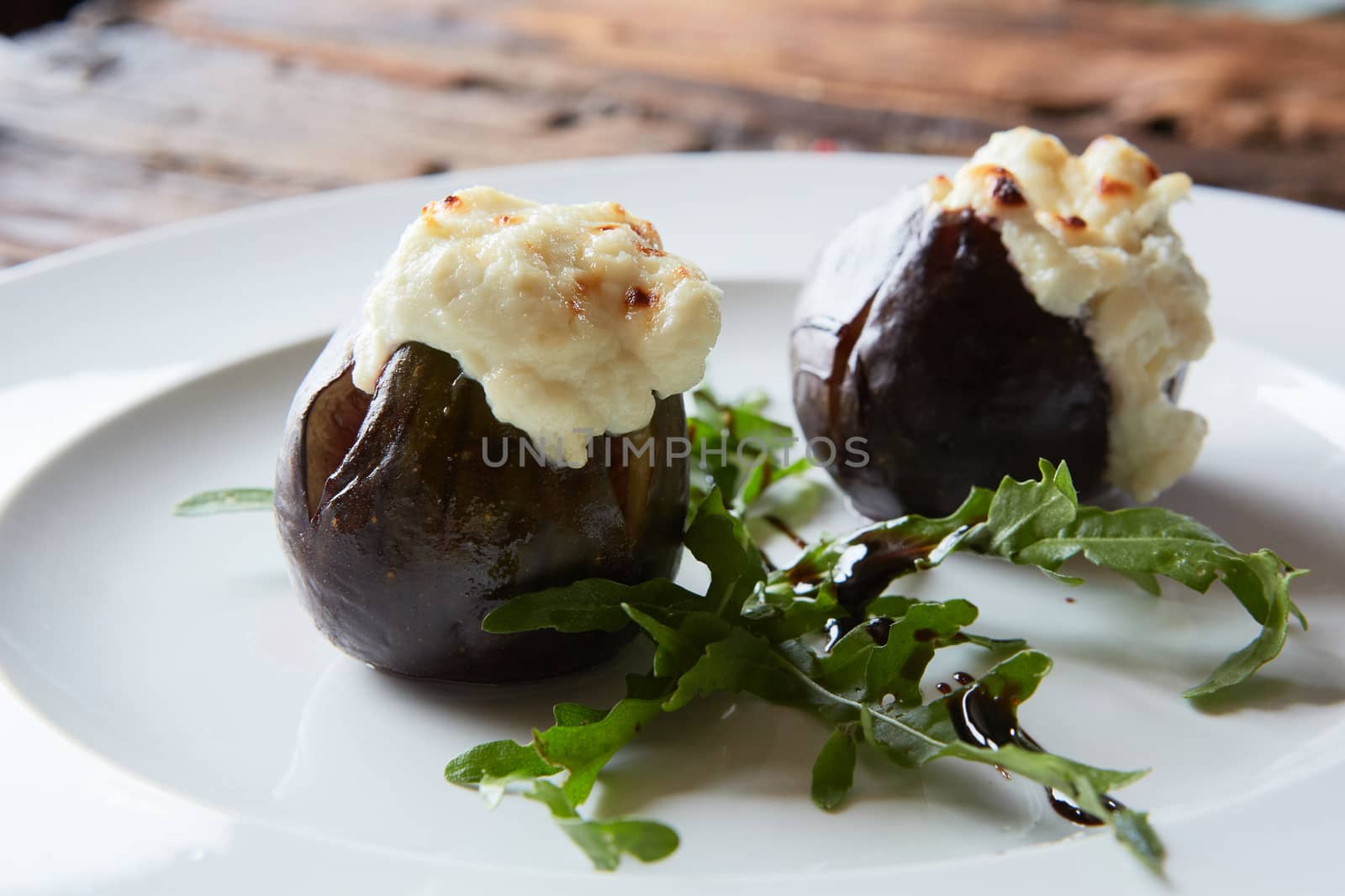 baked figs with goat cheese on wooden table.