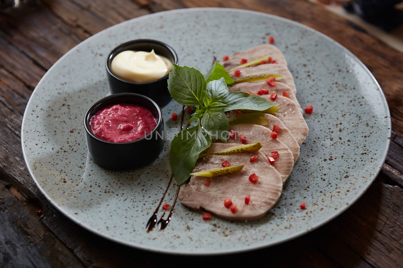 Sliced cold baked pork with herbs on blue plate.