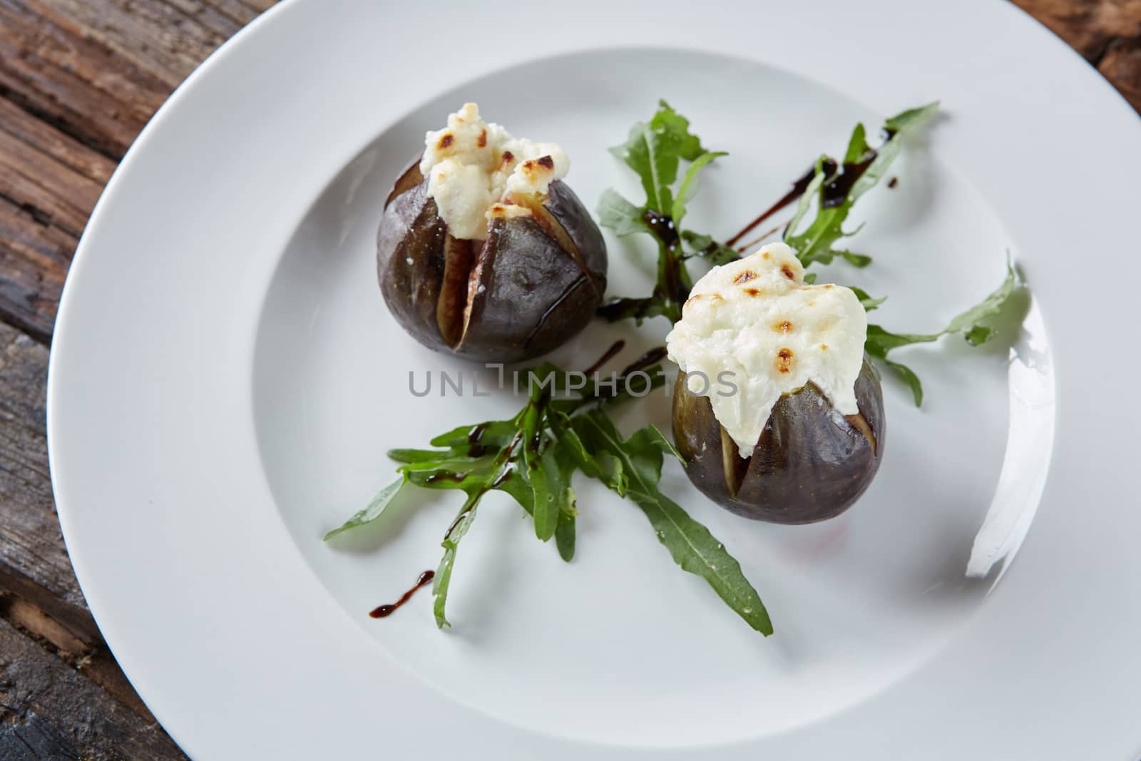 baked figs with goat cheese on wooden table.