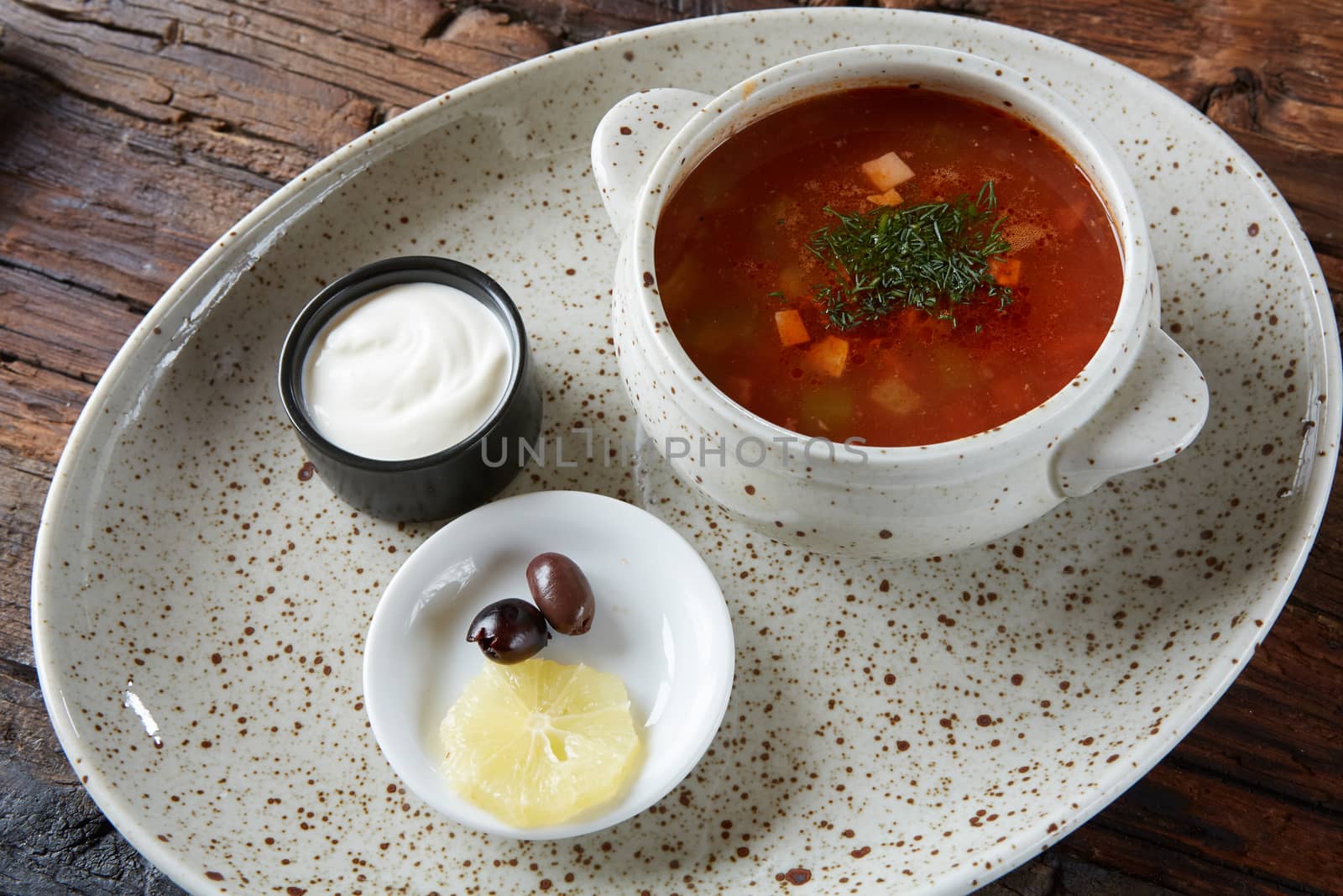 Soup saltwort with lemon, meat, pickles, tomato sauce olives in a bowl on a sacking