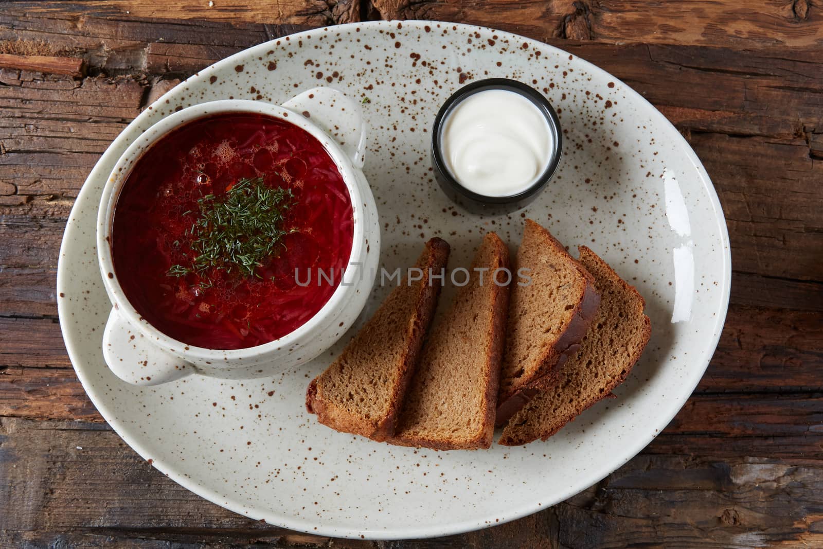 Traditional Ukrainian Russian borscht with white beans on the bowl. Plate of red beet root soup borsch on black rustick table. Beetroot soup Top view. Traditional Ukraine food cuisine.
