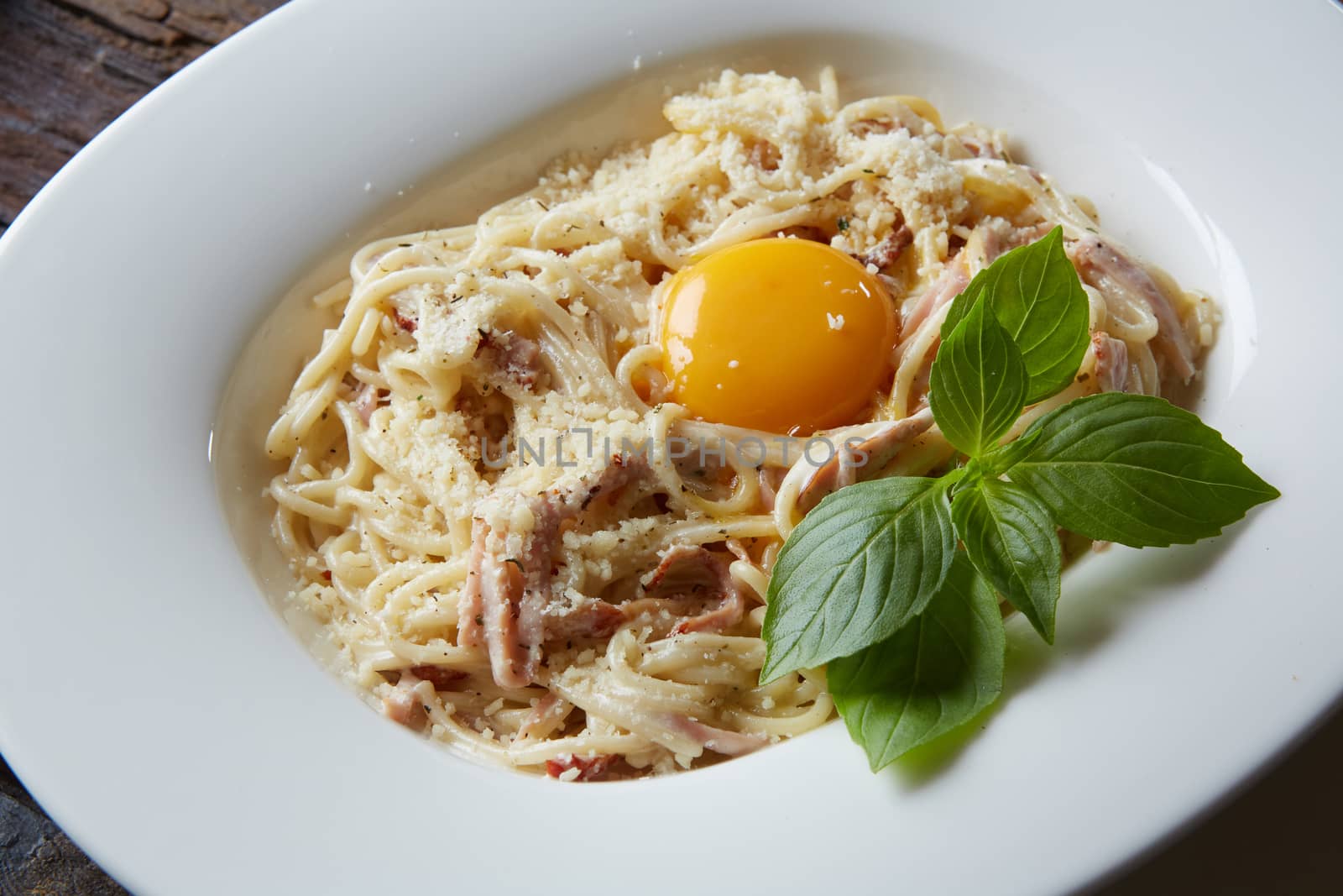 Pasta Carbonara on white plate with parmesan.