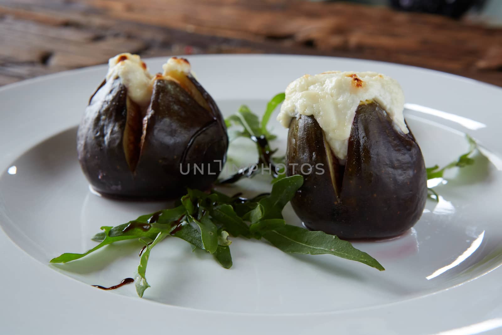 baked figs with goat cheese on wooden table.