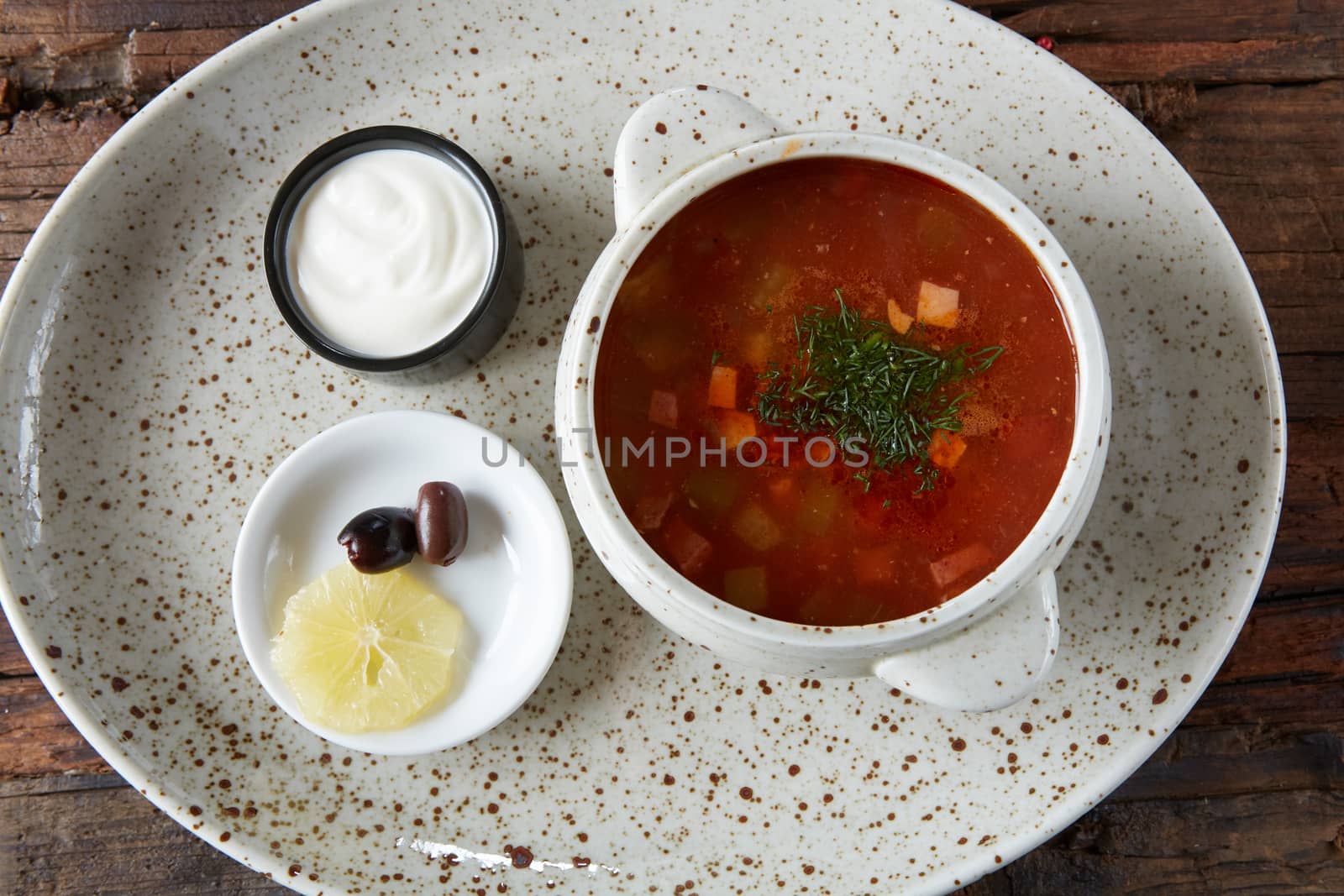 Soup saltwort with lemon, meat, pickles, tomato sauce olives in a bowl on a sacking