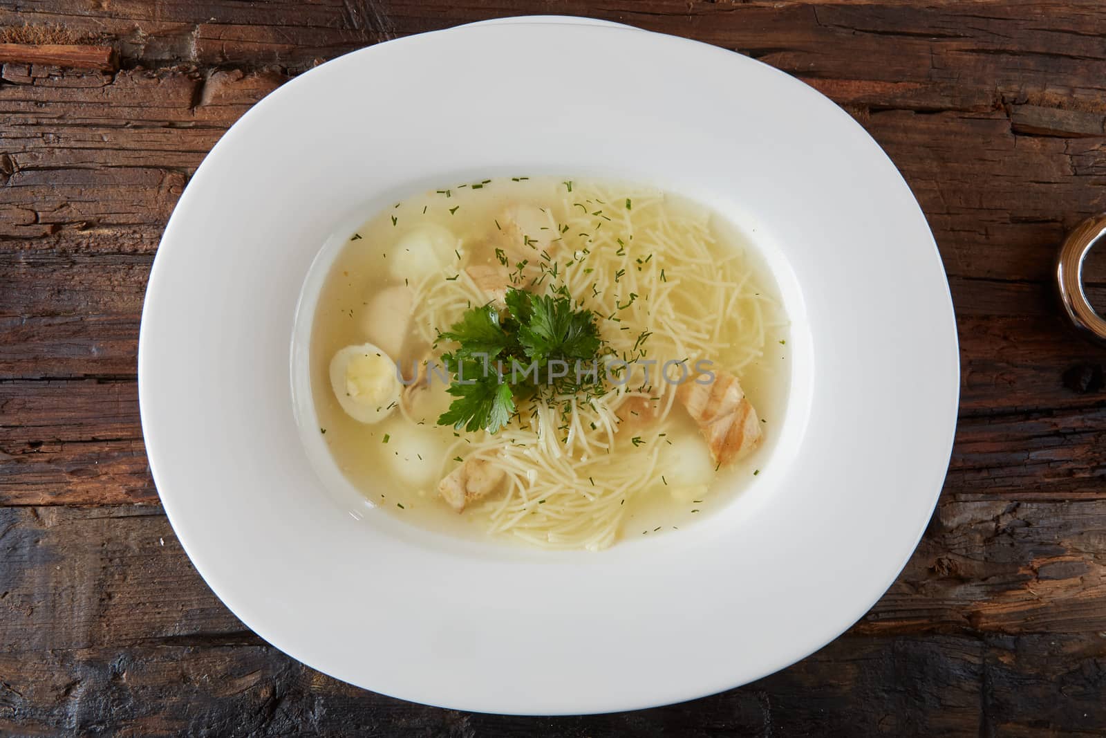 Chicken soup with noodles and vegetables in white bowl.