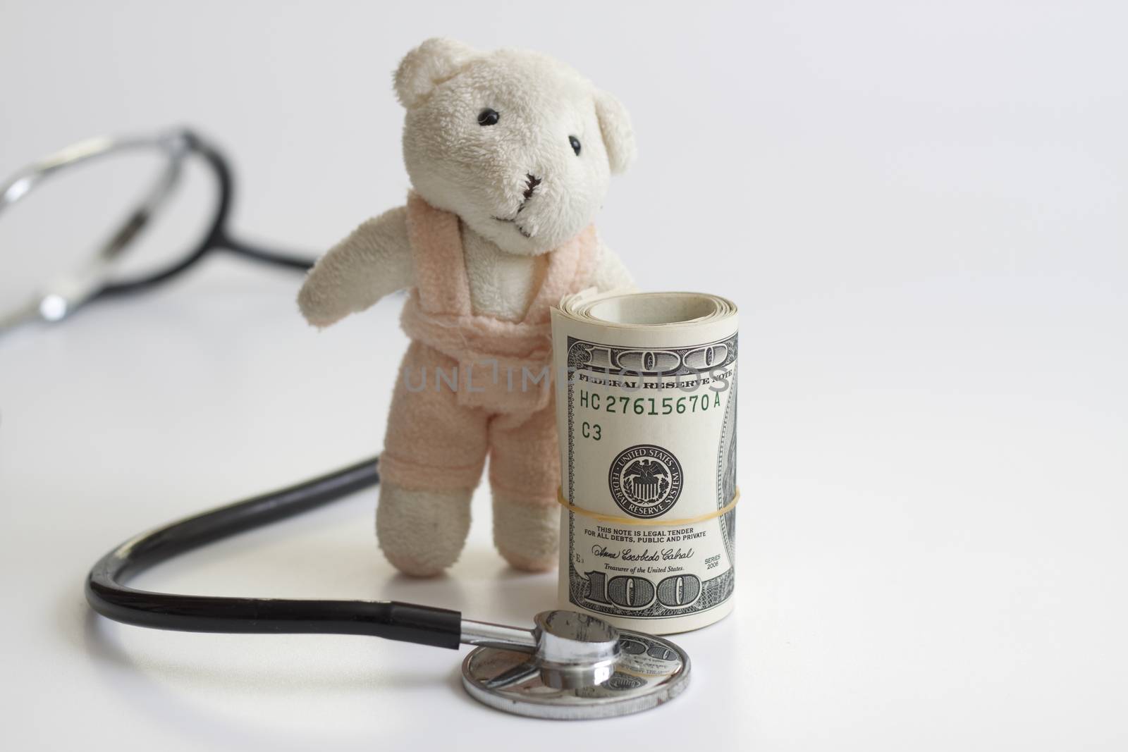 a stack of dollars  a stethoscope and a teddy bear the health insurance future