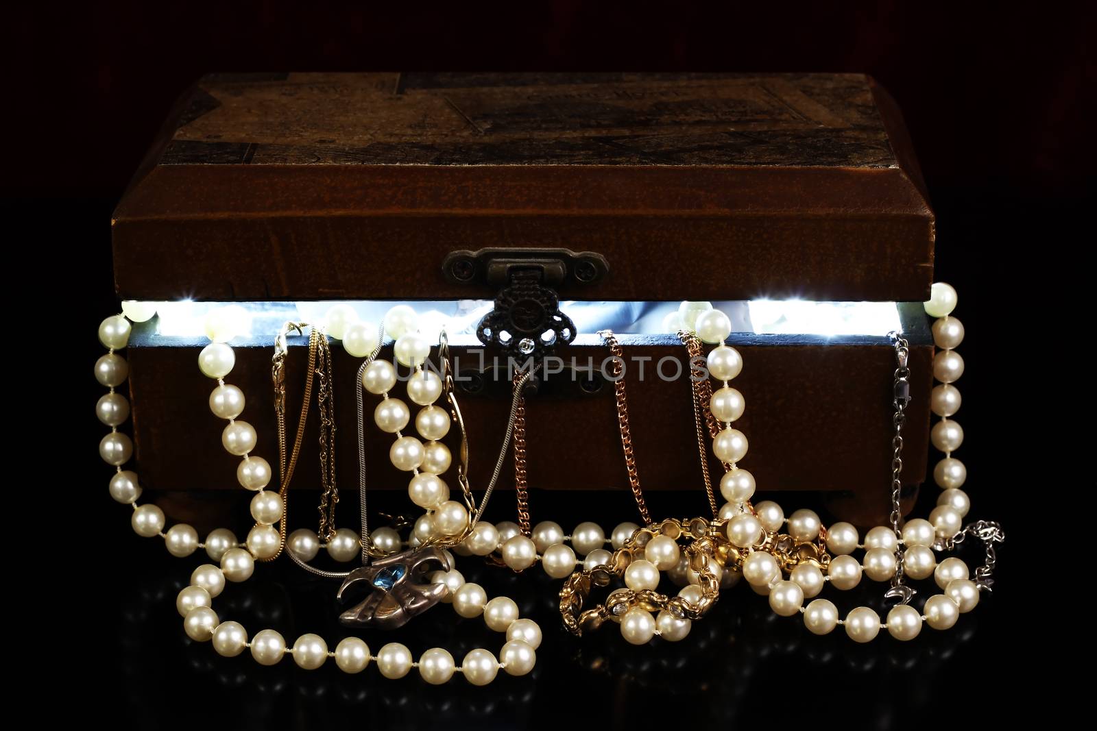 tresure chest with open lid light from within and jewelry with reflection