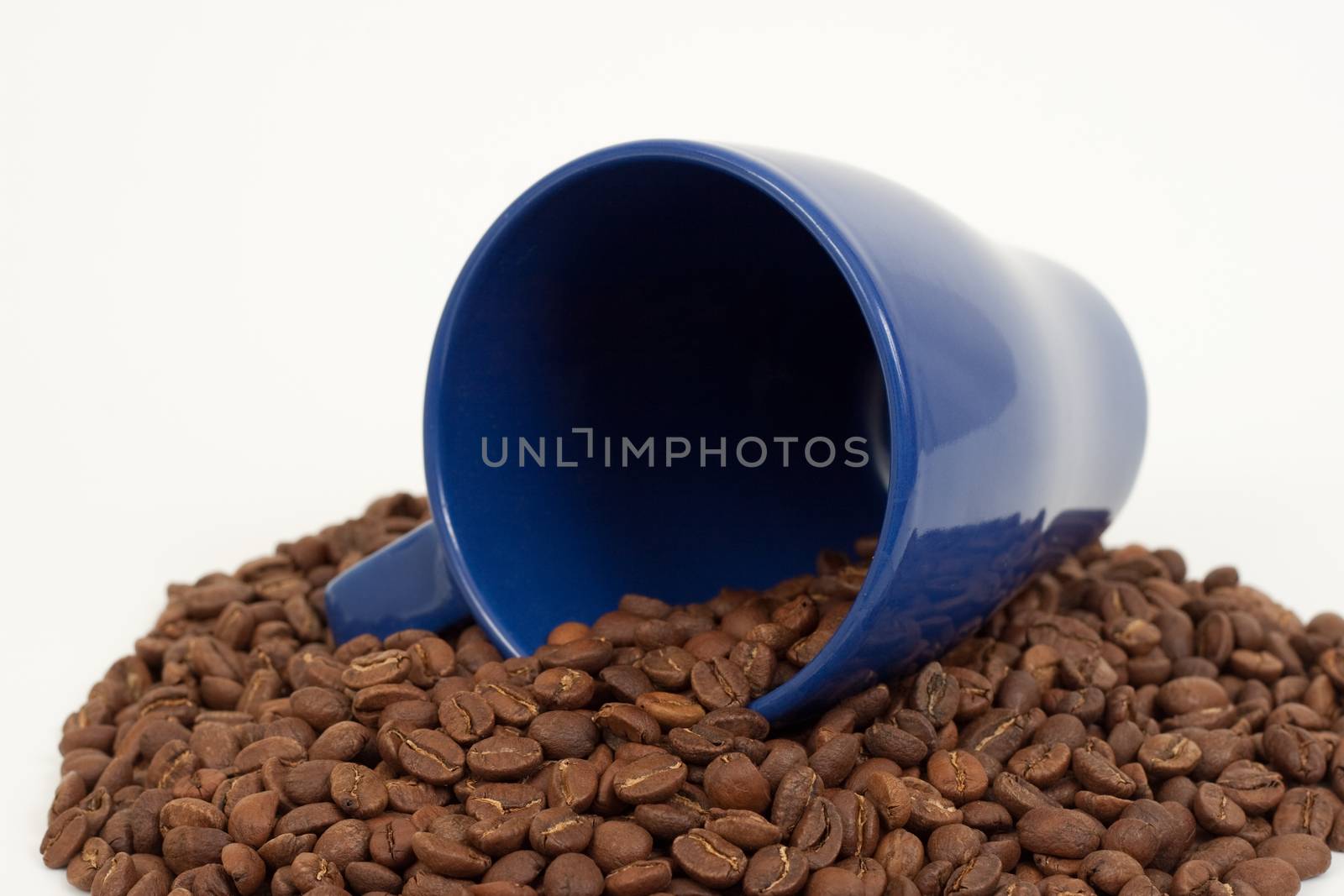 blue cup on top of  coffee beans white background