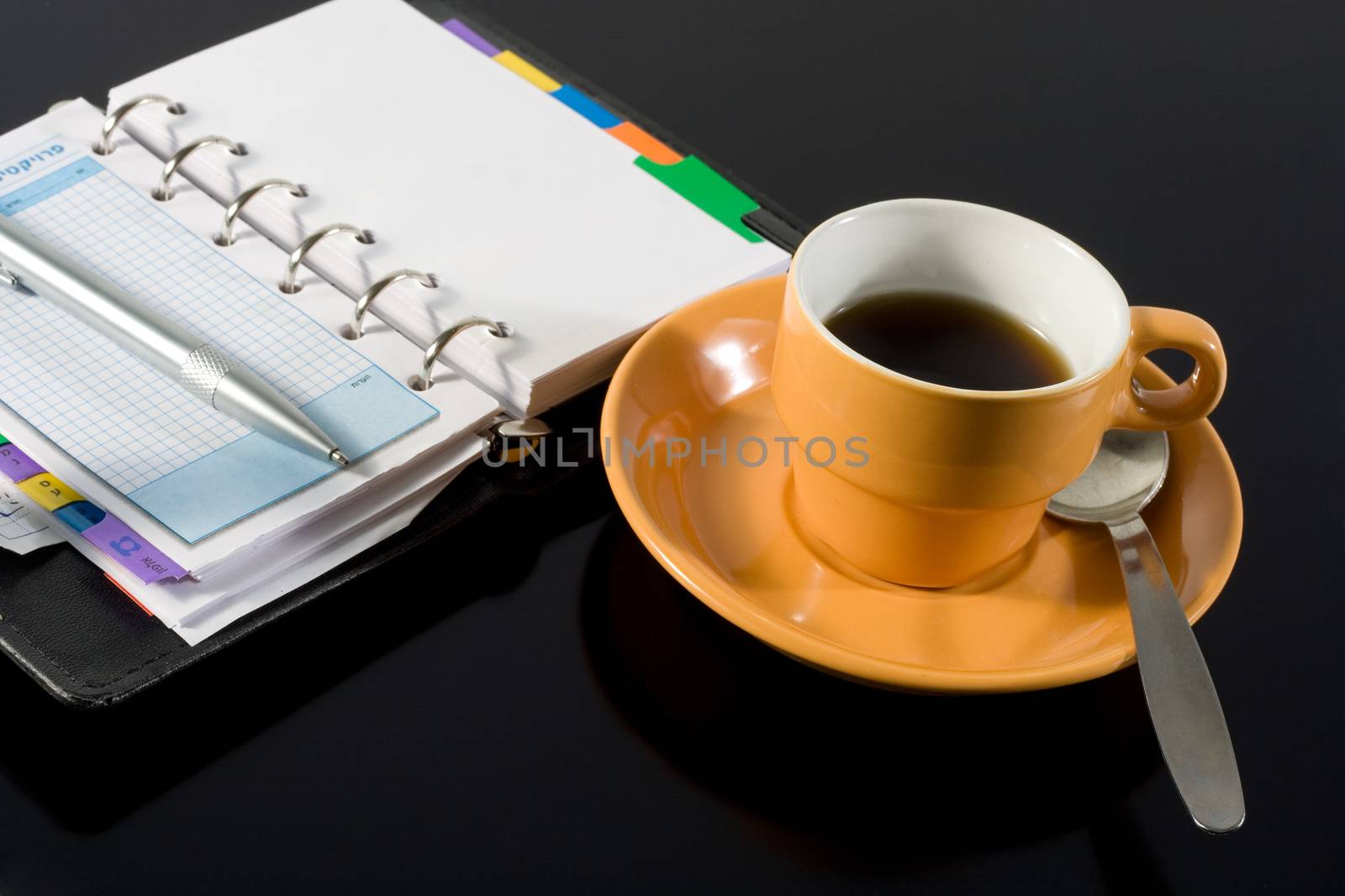 orange coffee cup and a notepad on black background
