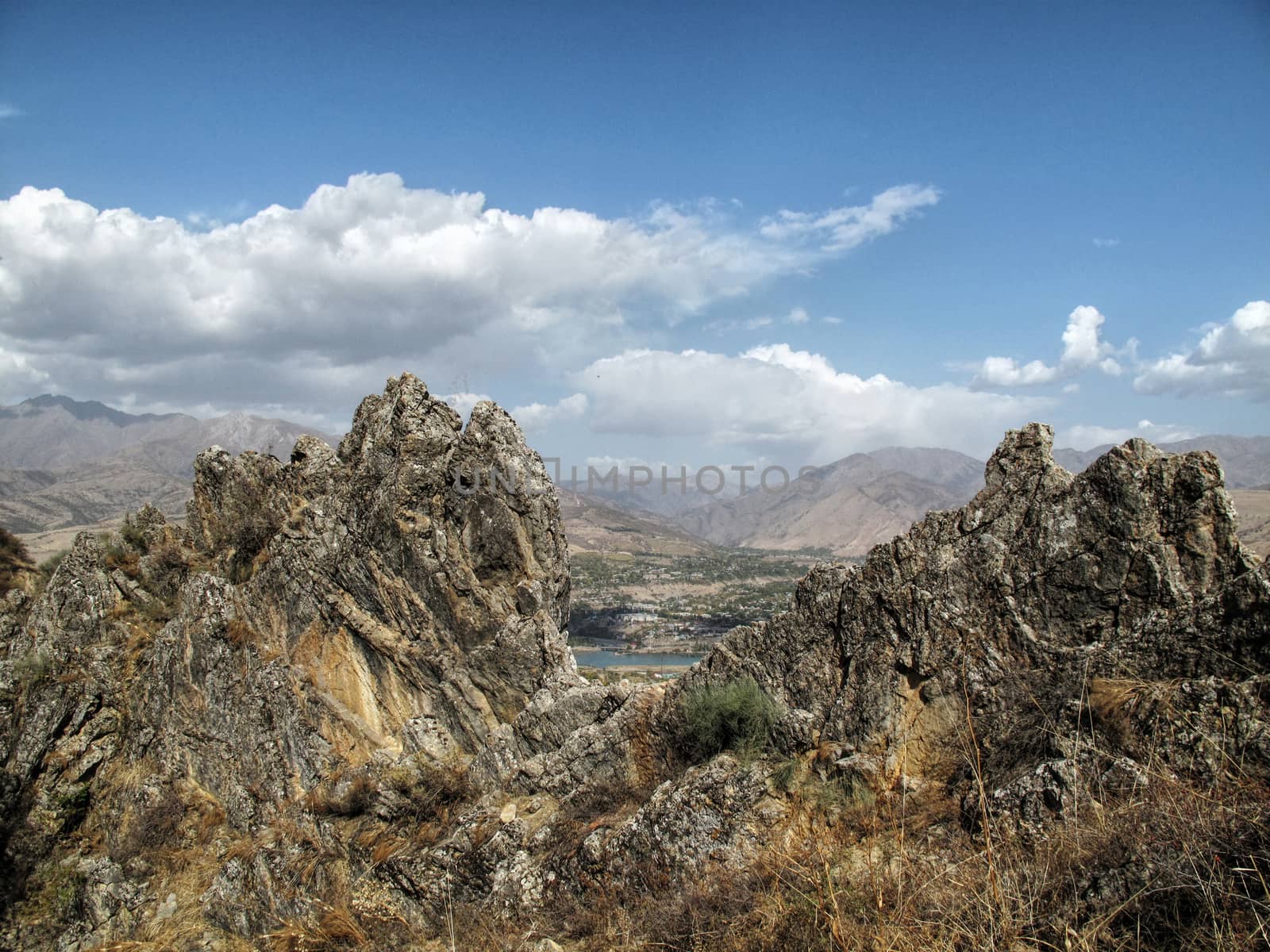 between the two mountain peaks is far and visible river and city
