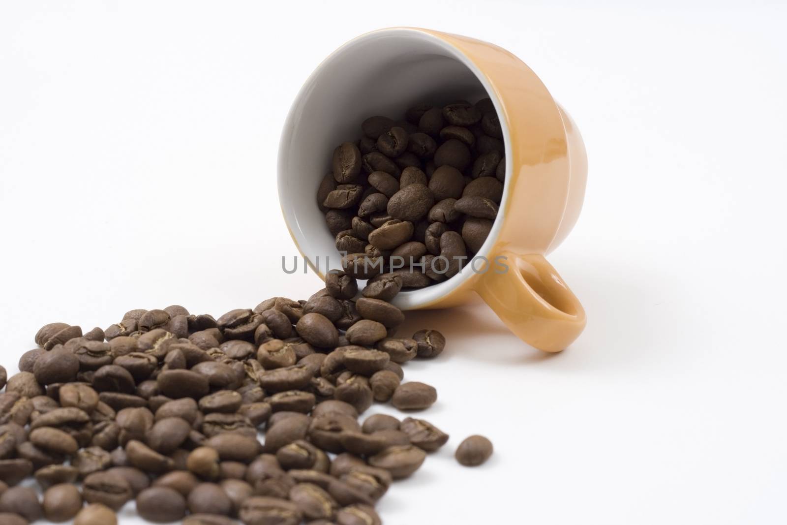 coffee beans pouring out from an orange coffee cup