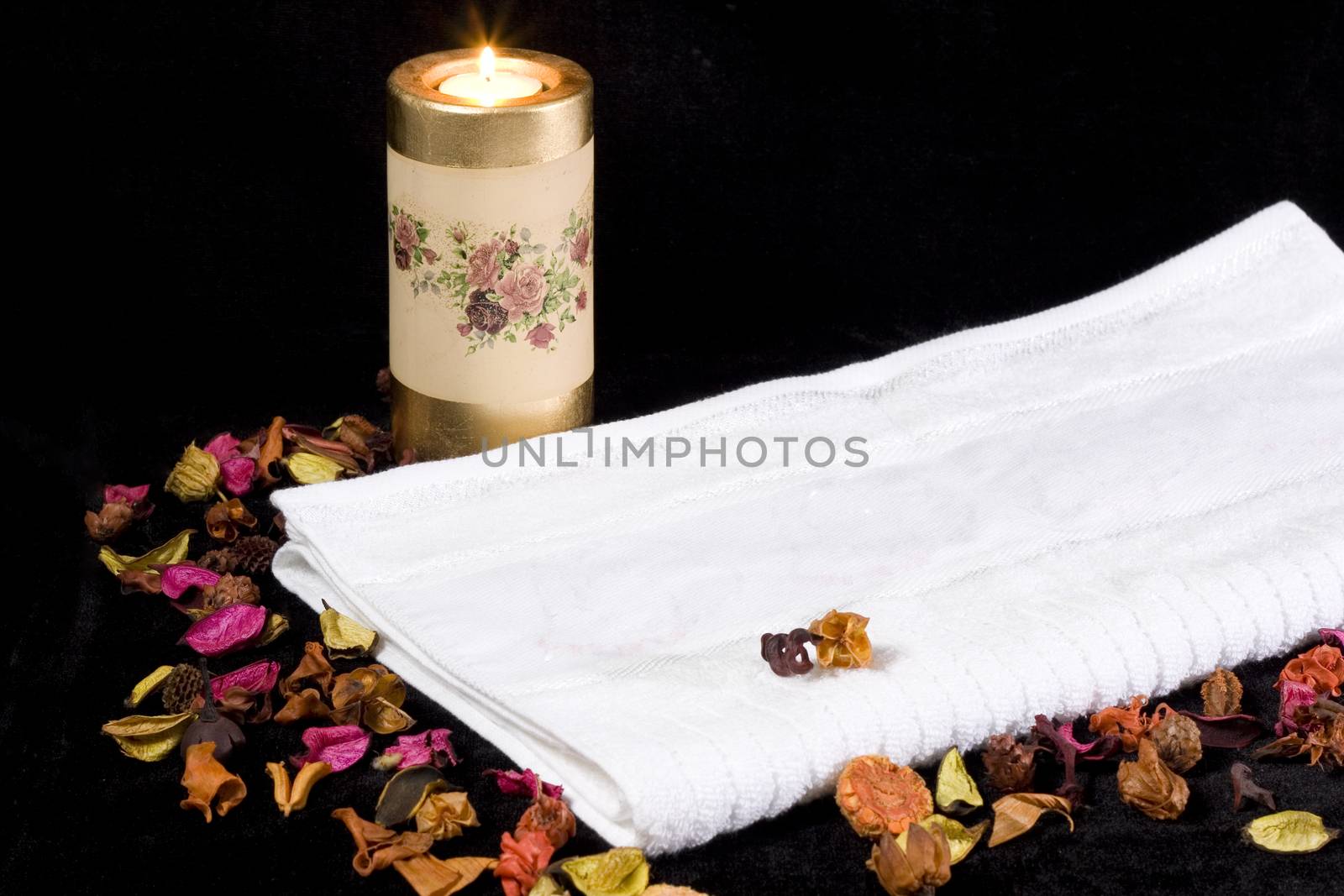 a white towel burning candle and dried flowers
