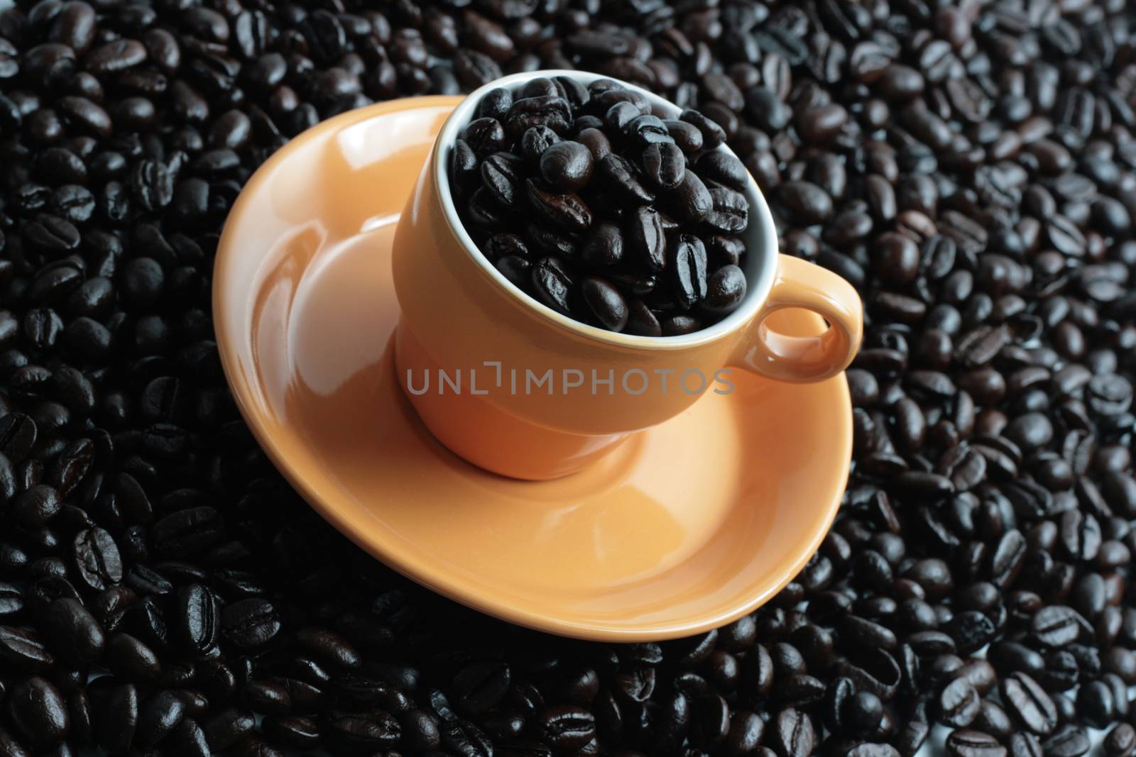 oranje coffee cup on full of coffee beans on coffee beans