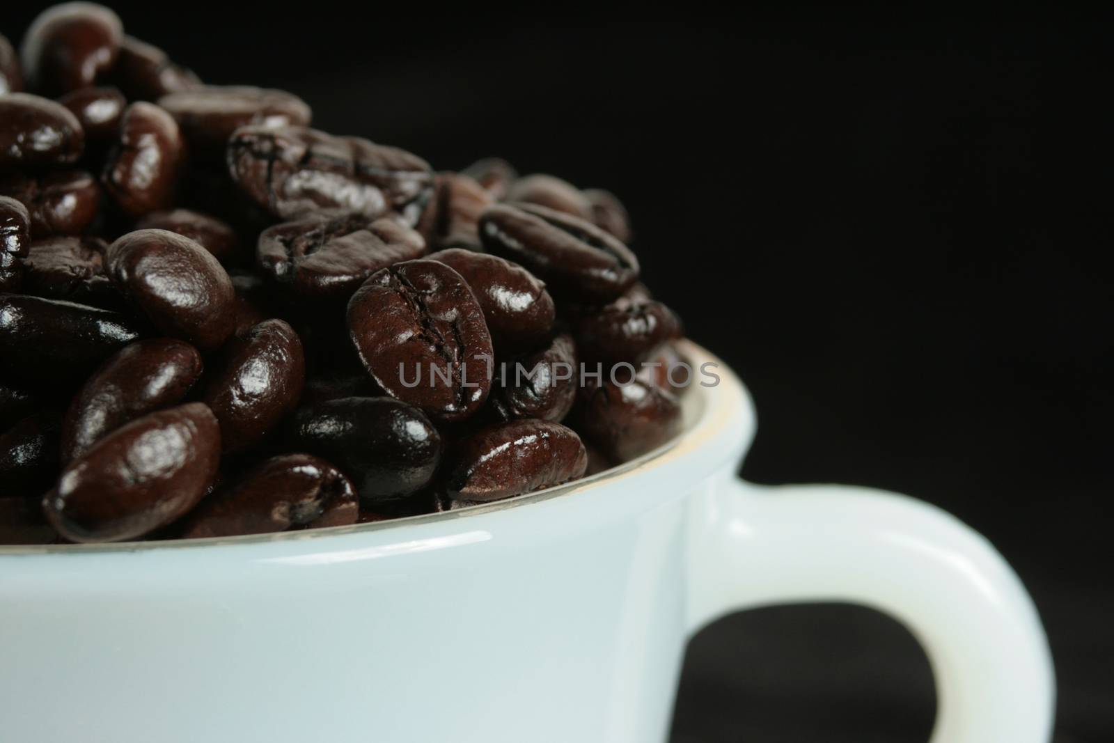a cup full of cofee beans on black background
