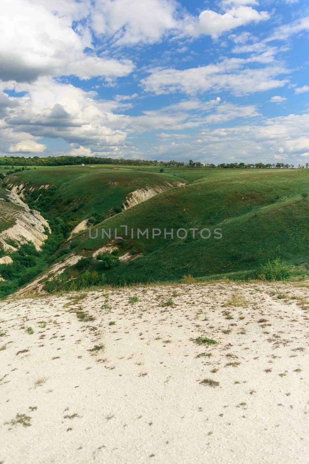 Beautiful view of grassy ravine on sky background with clouds, vertical shot.