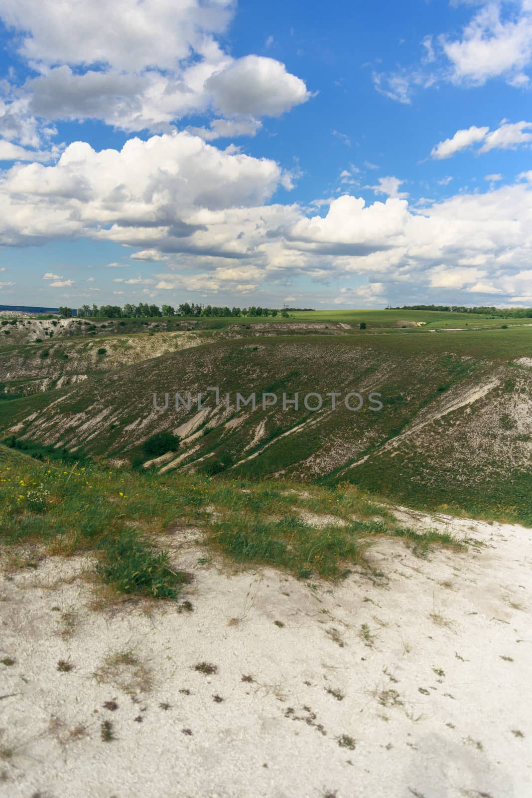 Beautiful view of grassy ravine on sky background with clouds, vertical shot.