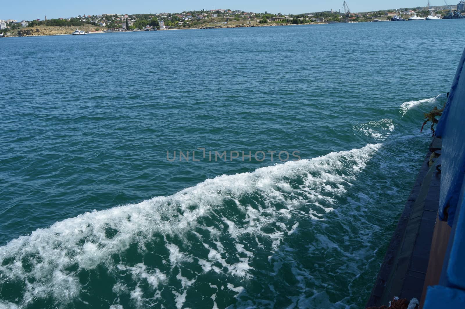 Background with wave and foam, trace on the surface of the water behind the fast moving ship.